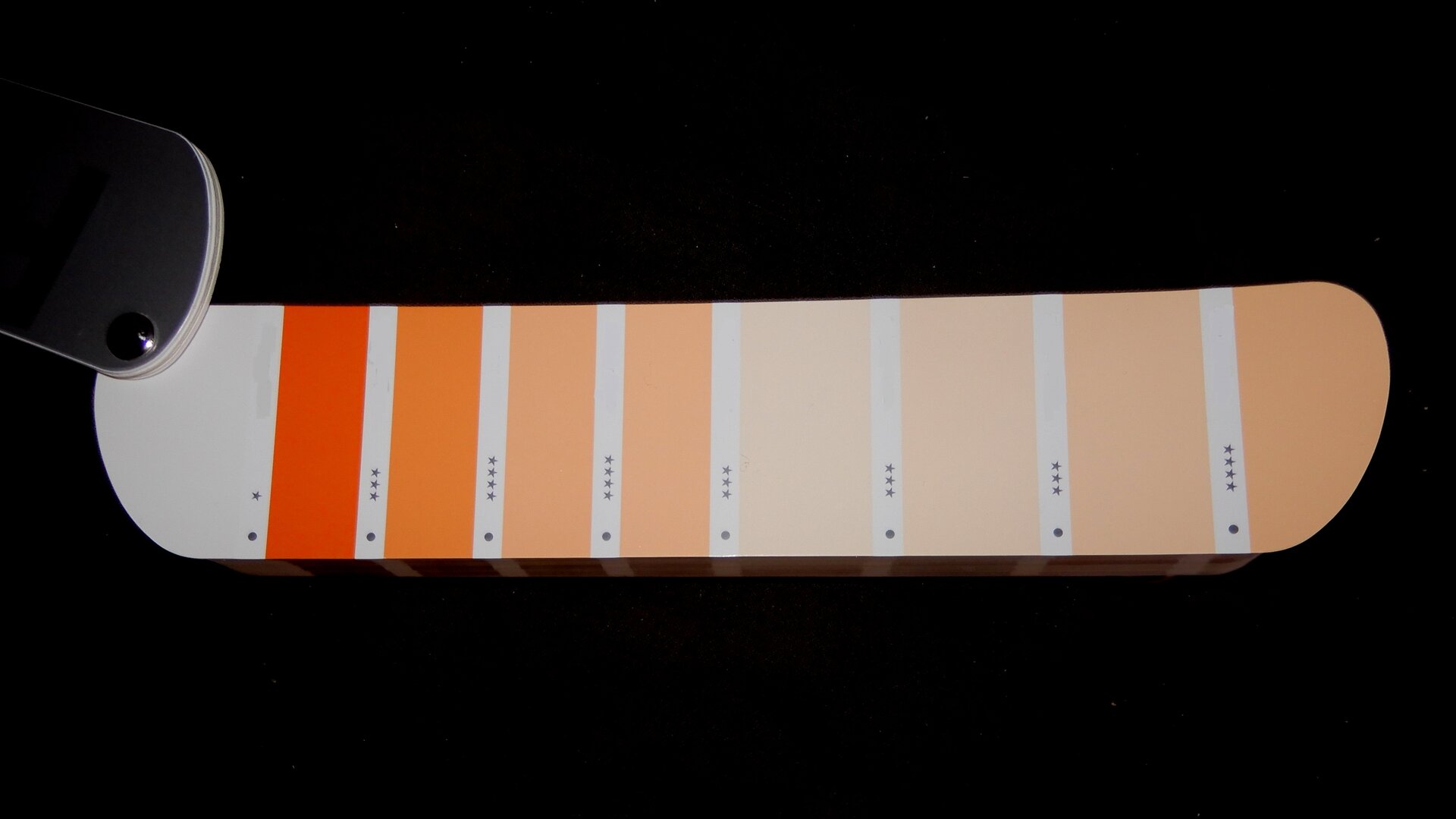 Ilustracja przedstawia próbnik kolorów. Ukazuje połączone paski, na których zamieszczone zostały kolory, tworzące zestawy monochromatyczne, pochodzące od koloru pomarańczowego, który jest rozjaśniany, aż do prawie bieli o pomarańczowym odcieniu.