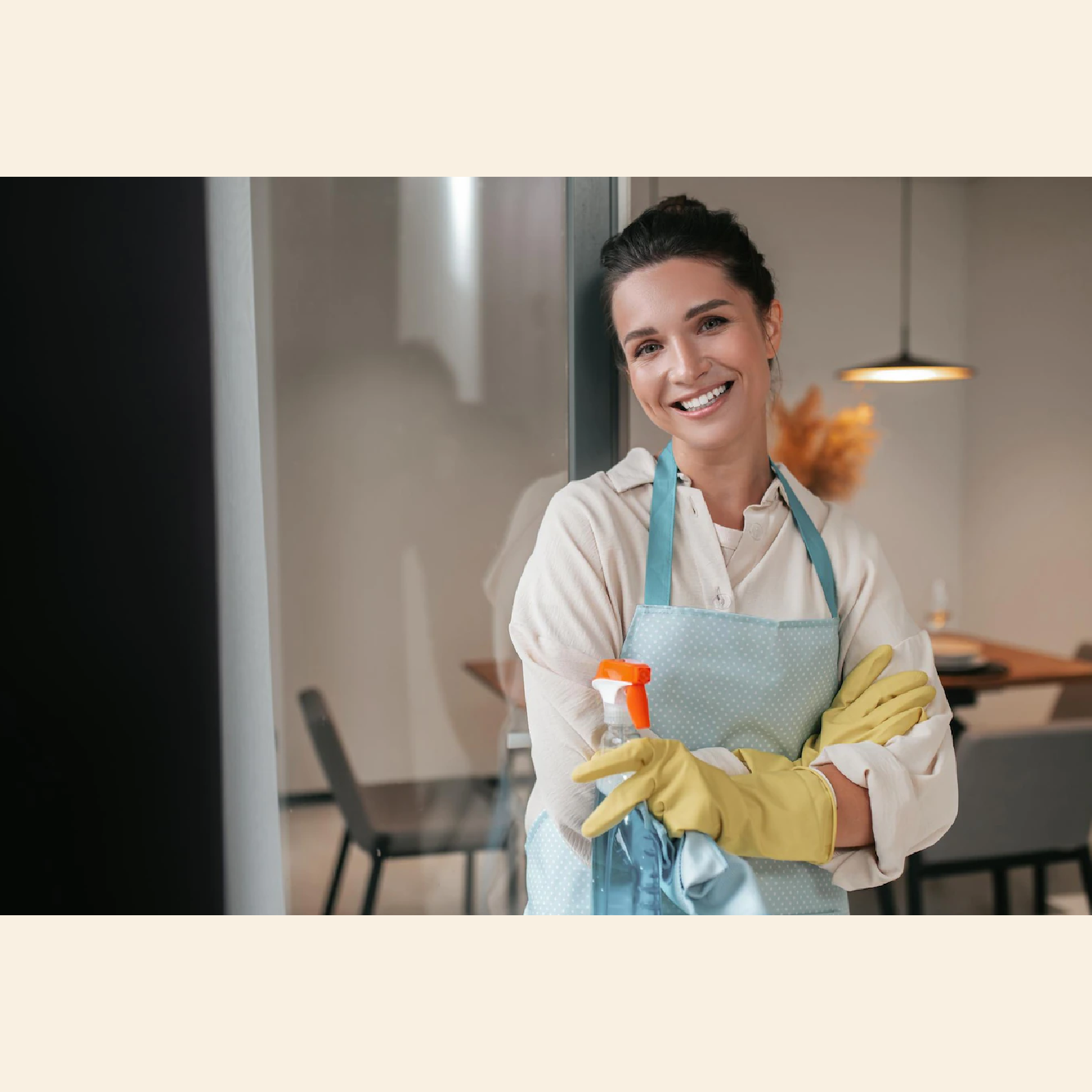 Ilustracja przedstawiająca uśmiechniętą kobietę, która ubrana jest w białą bluzkę i fartuch, założone ma gumowe rękawiczki. W dłoniach trzyma płyn do szyb oraz ścierkę.