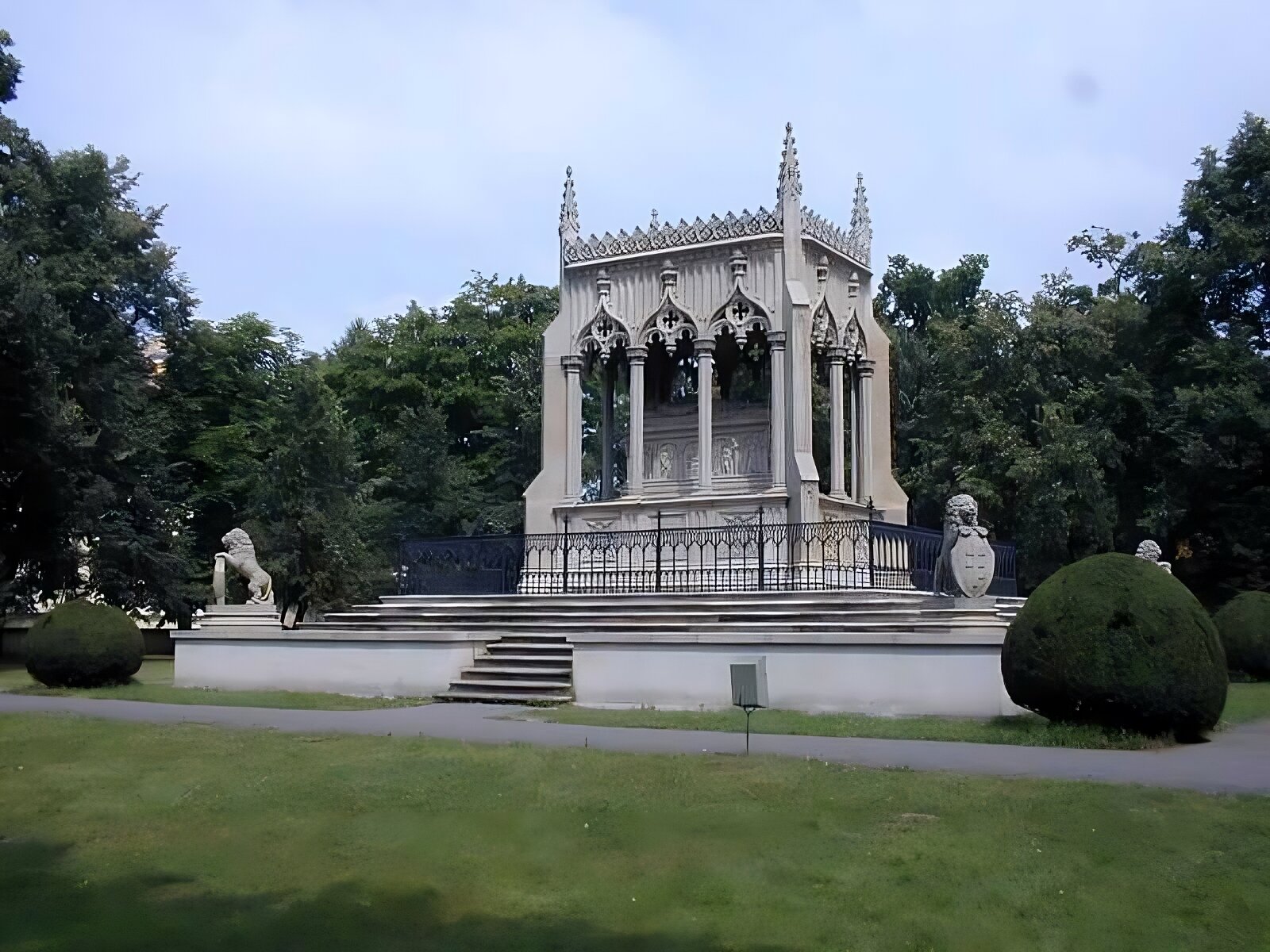 Zdjęcie przedstawia współczesne zdjęcie symbolicznego nagrobka rodziny Potockich w pobliżu pałacu w Wilanowie w Warszawie. Mauzoleum wykonano z piaskowca w stylu neogotyckim. Znajduje się on w otoczeniu parkowym, obramowany klombami na fragmencie trawnika. W tyle fotografii widoczne są drzewa. Do mauzoleum prowadzi widoczna na pierwszym planie aleja parkowa. W centrum obrazu jest zlokalizowany na cokole, do którego wchodzi się po schodkach, sarkofag z neogotyckim baldachimem, wspartym na czterech kolumnach z każdej strony. Nad baldachimem widoczne są sterczyny. Pod baldachimem jest nagrobek z postaciami na wierzchu. Jego boki pokrywają płaskorzeźby. Sarkofag otoczony jest metalową balustradą i prowadzą do niego schody. Na postumencie w rogach umieszczono cztery lwy, trzymające tarcze z herbami Pilawa Potockich i Drużyna Lubomirskich. 