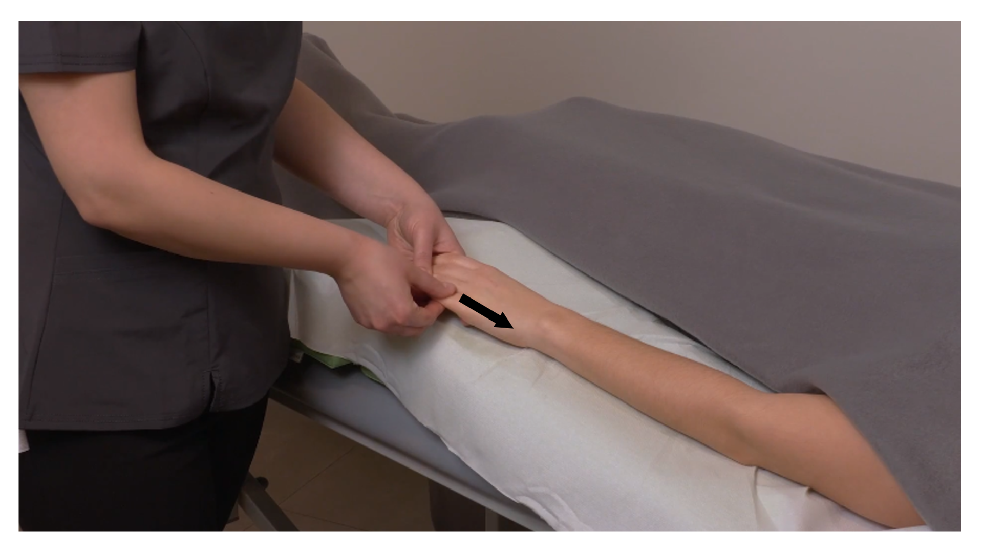 Zdjęcie pod tytułem głaskanie palców. Zdjęcie przedstawia ręce masażysty wykonujące posuwiste ruchy przy użyciu opuszków kciuków wzdłuż ręki pacjenta, od czubków palców do nadgarstka.