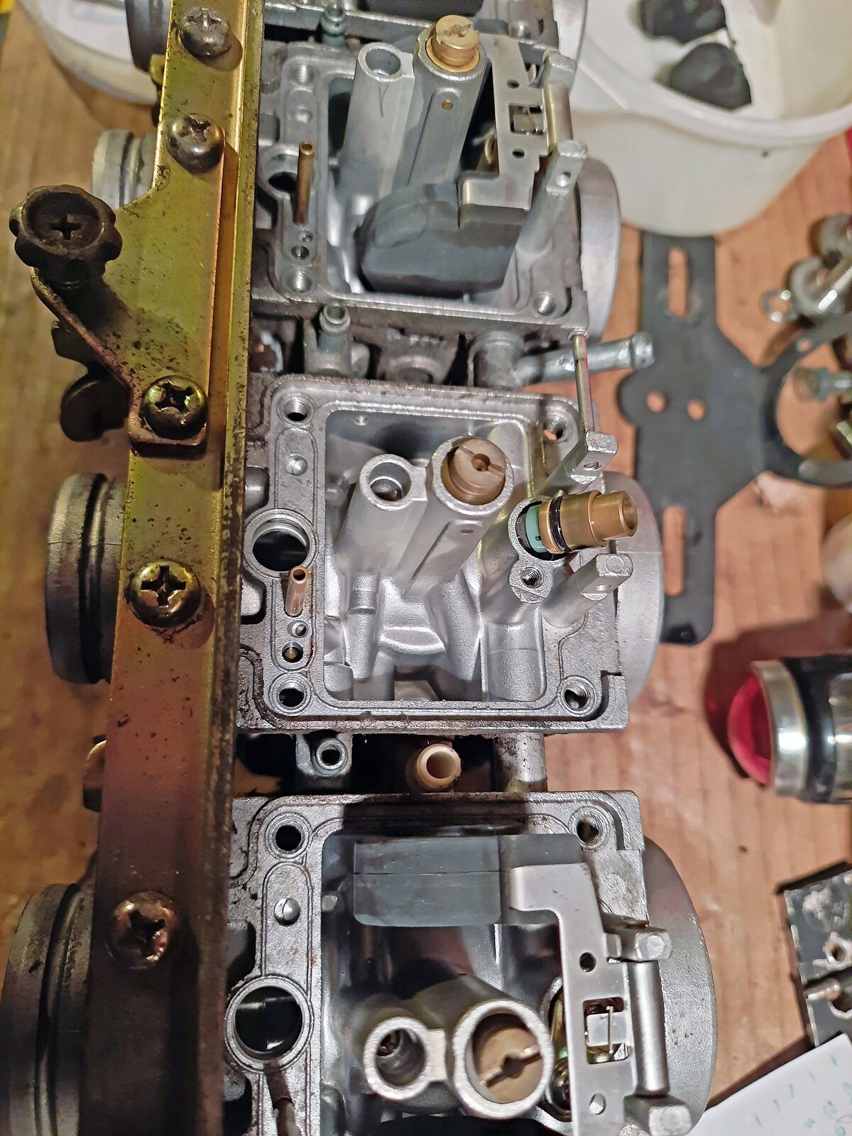 Na ekranie rozmontowany gaźnik. W komorze pływakowej środkowego gaźnika wymontowany pływak i wyjęty korpus zaworka iglicowego.