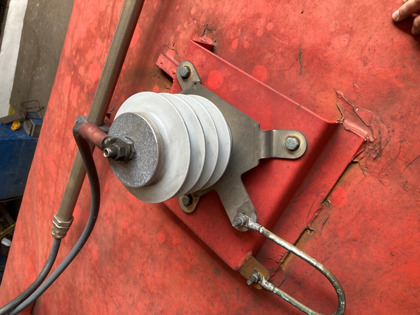 Zdjęcie przedstawia odgromnik zaworowy przymocowany na ramie umieszczonej na dachu wagonu. Jego budowa składa się z podstawy, łączonej z konstrukcją pojazdu za pomocą czterech śrub, iskiernika, który ma postać czterech krążków, zakończonych elementem magnetycznym. oraz dwóch przewodów elektrycznych - jeden stykający się z podstawą, a drugi z elementem magnetycznym.