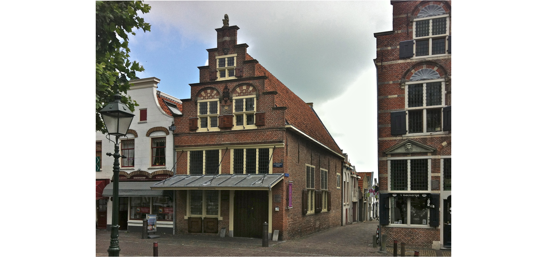 Zdjęcie przedstawia budynki przy uliczce. Zabudowa jest historyczna, widać ozdobne mury i okna.