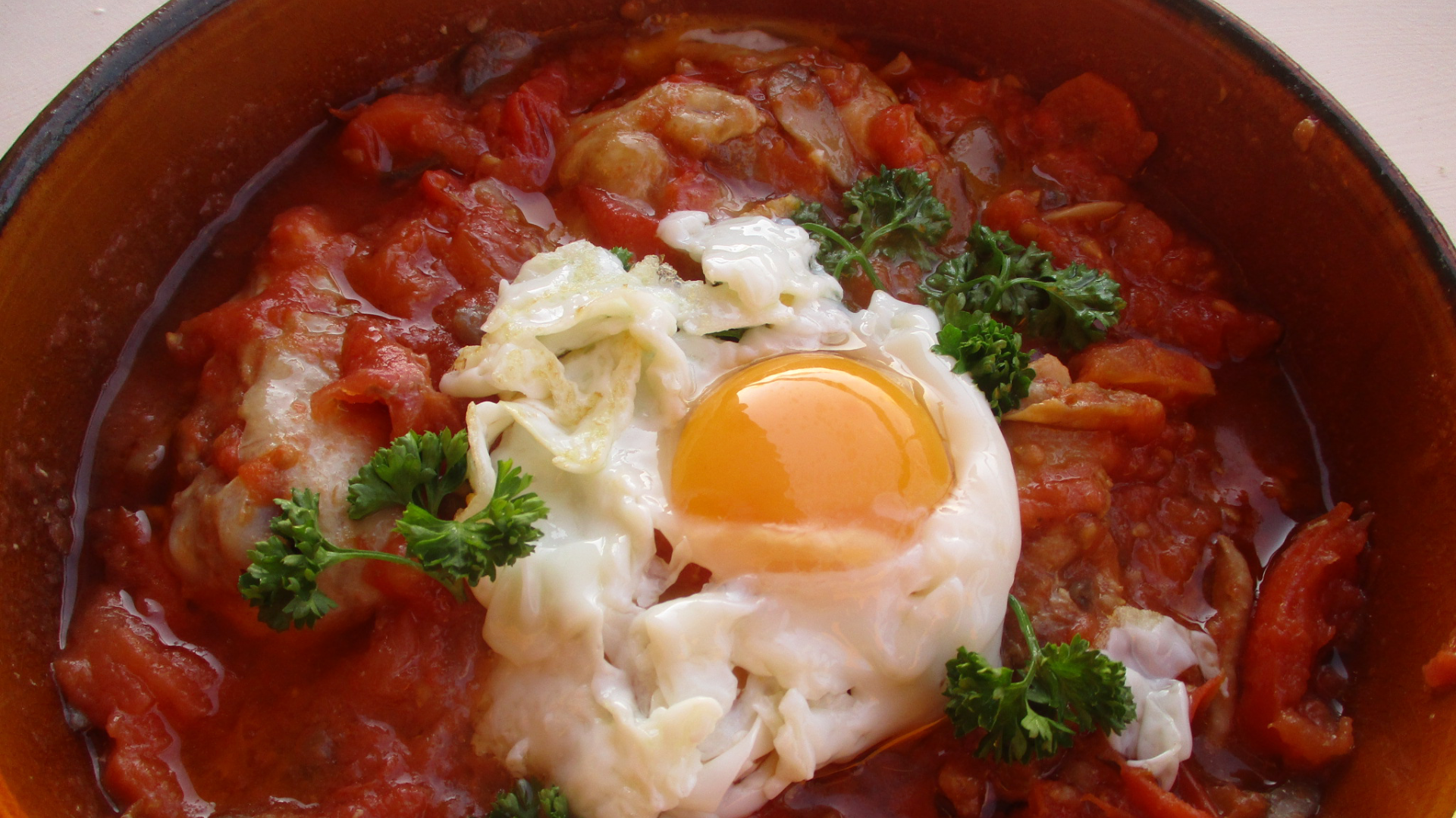 Zdjęcie przedstawia typowe włoskie danie sylwestrowe. Jest to kurczak w pomidorach z sadzonym jajkiem na wierzchu.