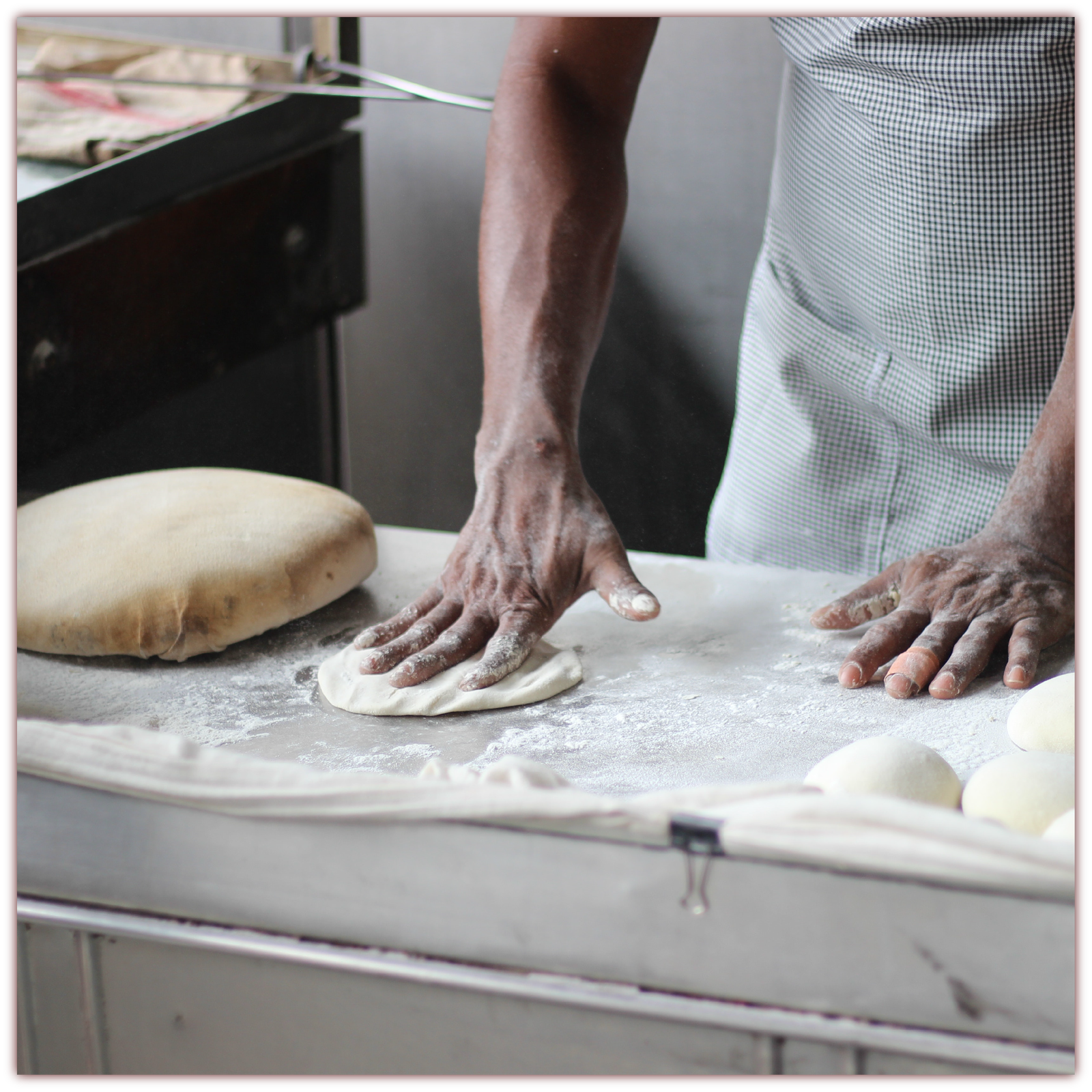 Grafika przedstawia mężczyznę w fartuchu formującego ciasto na stolnicy.