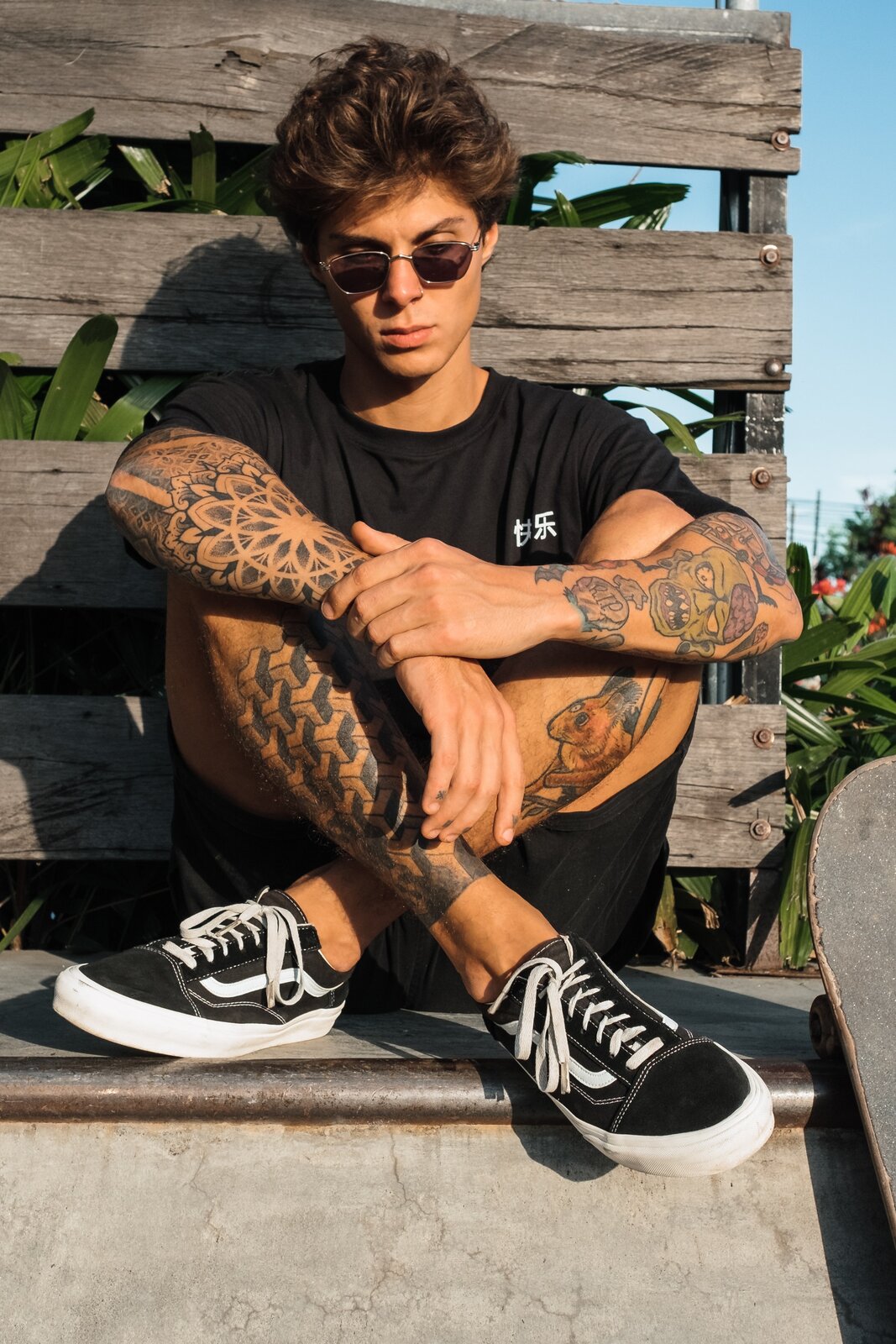 Zdjęcie przedstawia chłopaka, który na rękach i nogach ma tatuaże