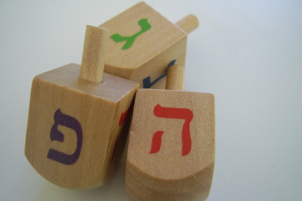 Fotografia przedstawiająca Dreidel, czyli czteroboczny bączek z pojedynczą literą hebrajską na każdym boku, który służy do uprawiania tradycyjnej żydowskiej gry podczas święta Chanuka.