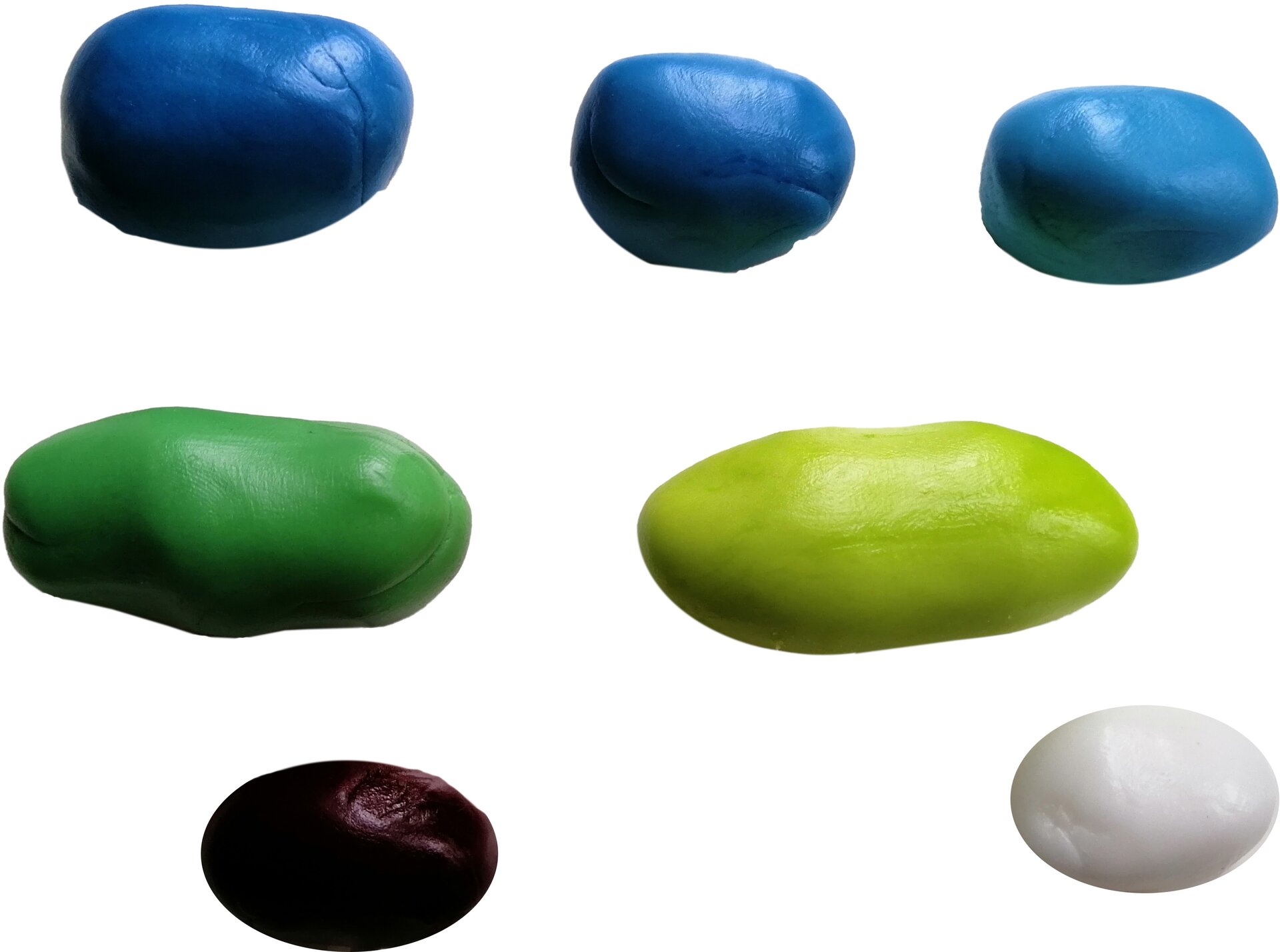 Zdjęcie przedstawia masę cukrową. Widoczne są różnej wielkości kulki lub spłaszczone kulki masy cukrowej w kolorze niebieskim, ciemnozielonym, jasnozielonym, czarnym i białym.