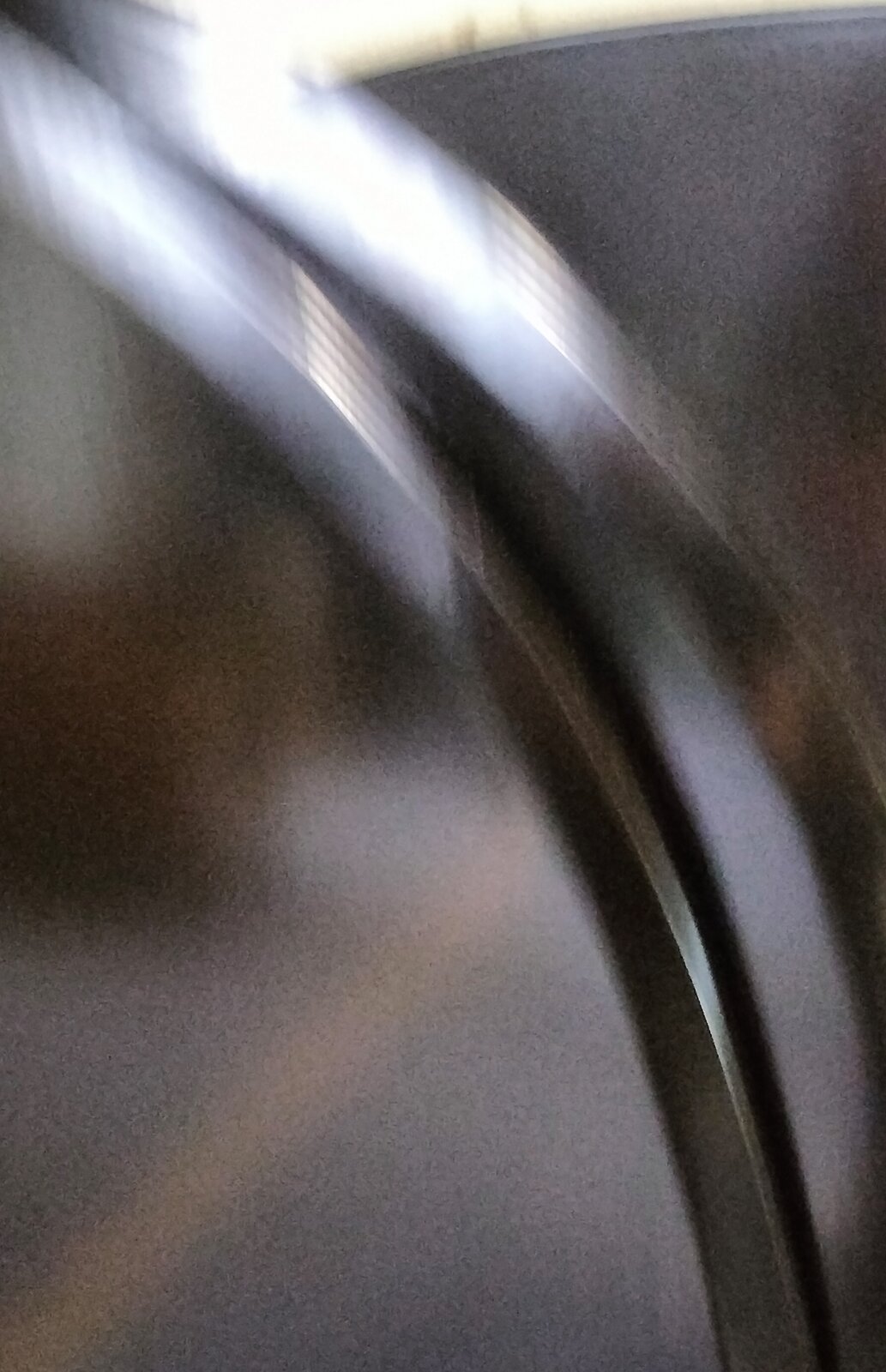 Zdjęcie przedstawia element obudowy fortepianowej polakierowany czarnym lakierem poliestrowym. Widoczna jest rozmyta błyszcząca powierzchnia w kolorze ciemnoszarym i srebrnym.