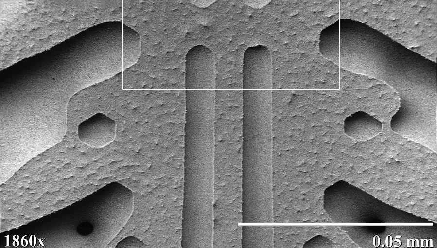Zdjęcie mikroskopowe przedstawia zbliżenie tysiącosiemsetsześćdziesięciokrotne na kryształ śniegu. Widoczne są kształtne żłobienia w ramieniu gwiazdy kryształu śniegu.
