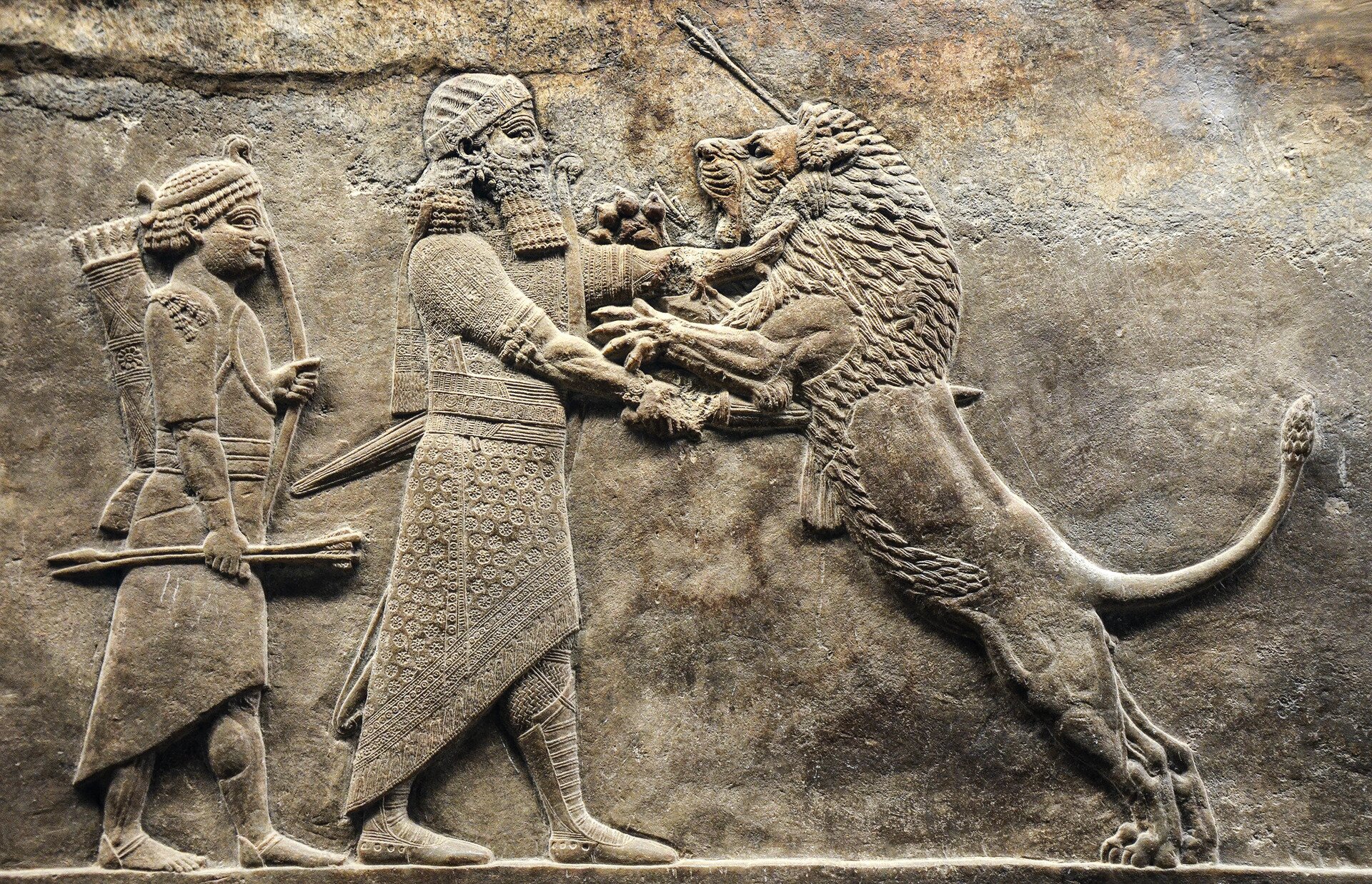 Fotografia płaskorzeźby z londyńskiego muzeum przedstawiająca asyryjskiego króla polującego na lwa.