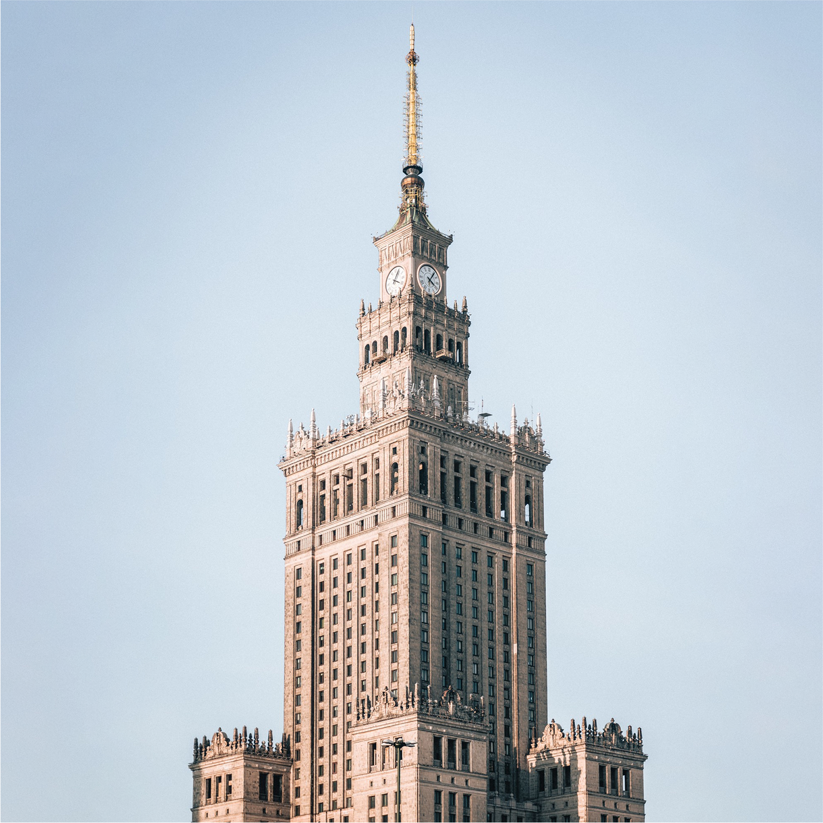 Ilustracja przedstawia Pałac Kultury w Warszawie. Na szczycie pałacu, widoczny jest zegar. Pałac ma strzelistą wieżę oraz dużo okien.