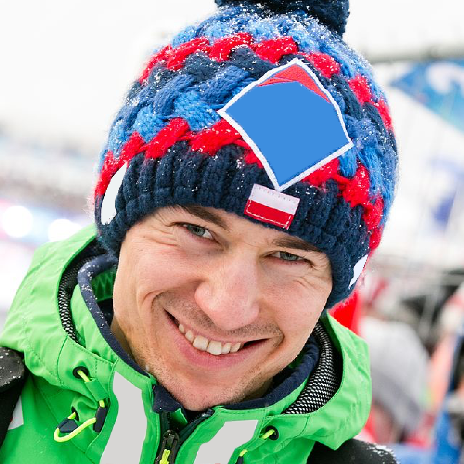 Zdjęcie przedstawia Twarz uśmiechniętego Kamila Stocha w czapce zimowej z polską flagą.