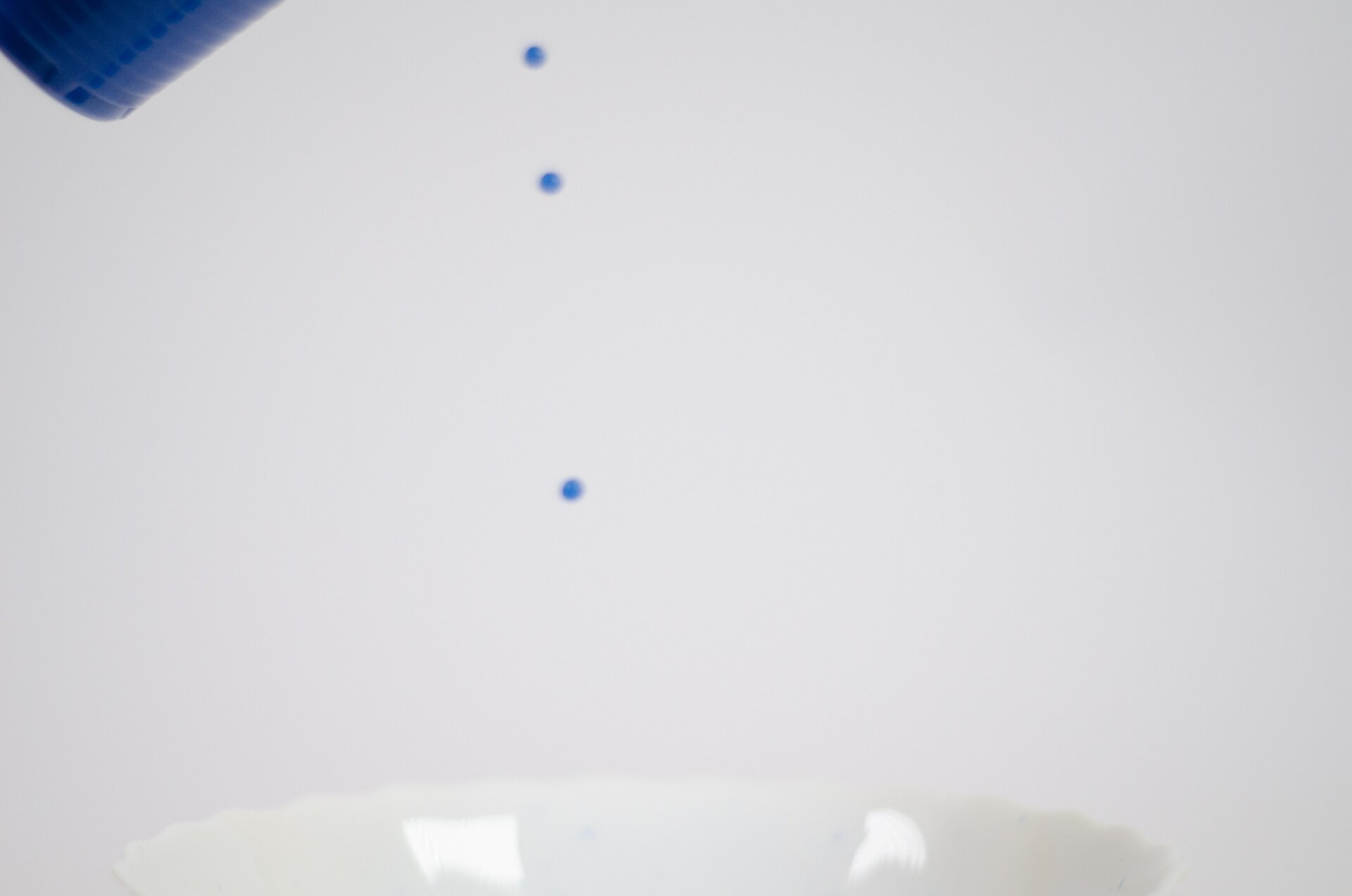 Fotografia przedstawiająca lekko rozmyte krople niebieskiej cieczy.