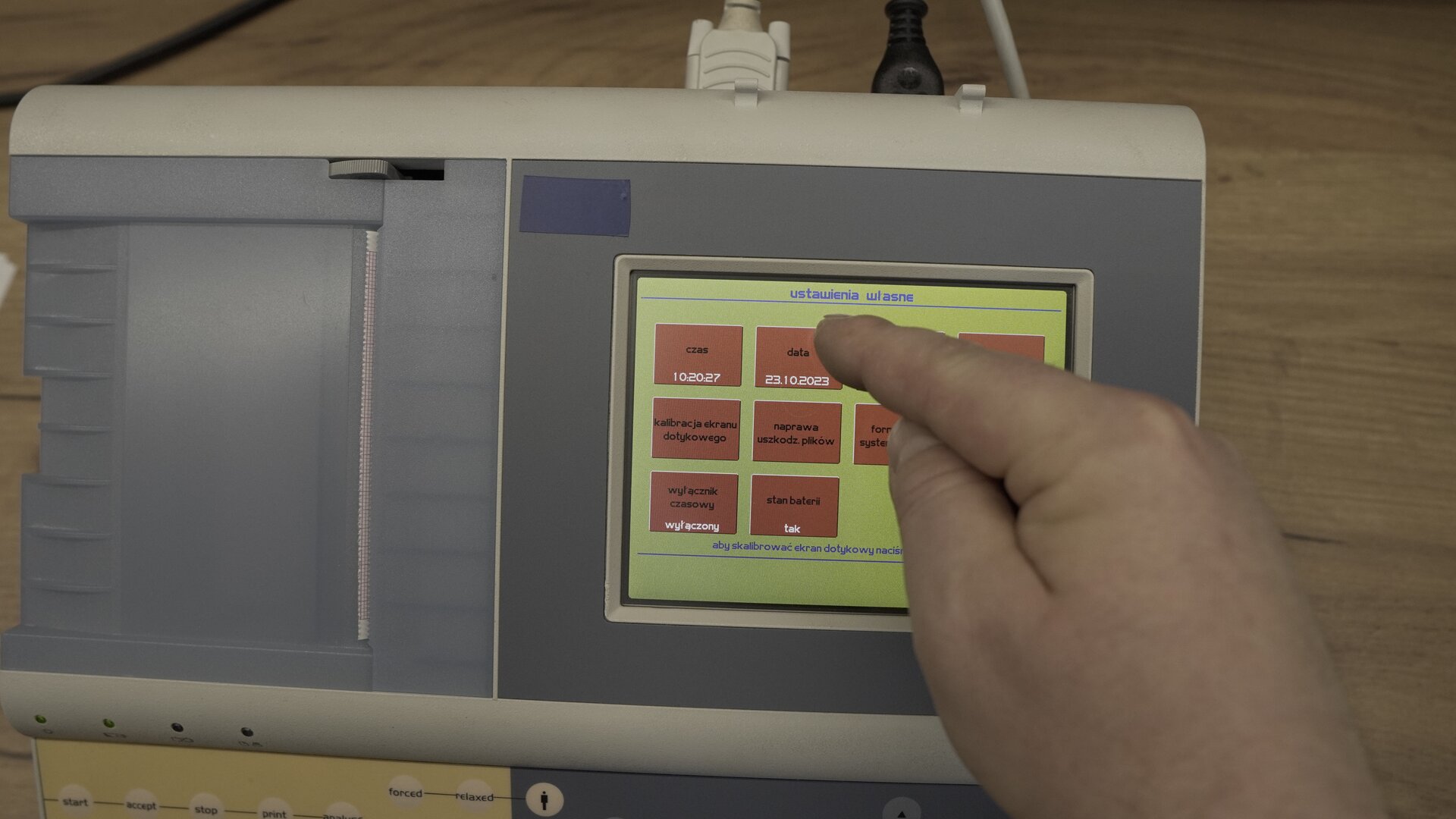 Na zdjęciu technik wybiera na klawiaturze ekranowej spirometru przycisk Data.
