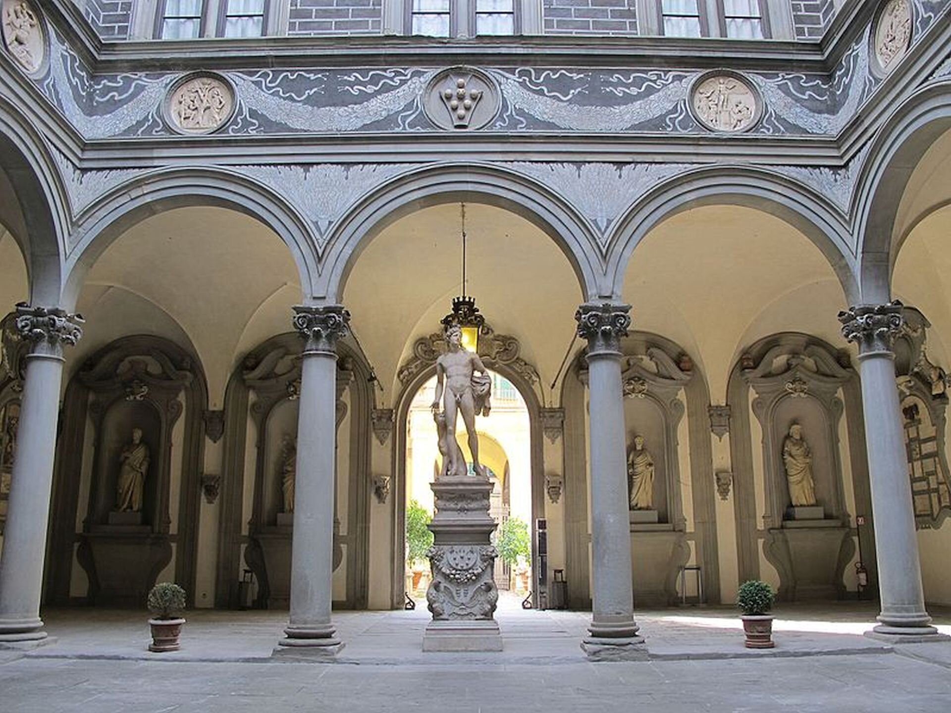 Ilustracja przedstawia zdjęcie wnętrza „Palazzo Medici” (Pałac Medyceuszy) we Florencji. Na ilustracji widoczna jest ogromne pomieszczeni z kolumnadą oraz łagodnymi łukami. Pasmo fryzu ciągnącego się ponad nimi udekorowane jest okrągłymi medalionami, połączonymi namalowanym motywem girland. Wnętrze medalionów wypełniają płaskorzeźbione motywy i sceny. Wnętrze zdobią także rzeźby antyczne. Poniżej został ukaazany czarno-biały rysunek przedstawiający florenckiego rzeźbiarza, architekta i inżyniera Filippo Brunelleschi.