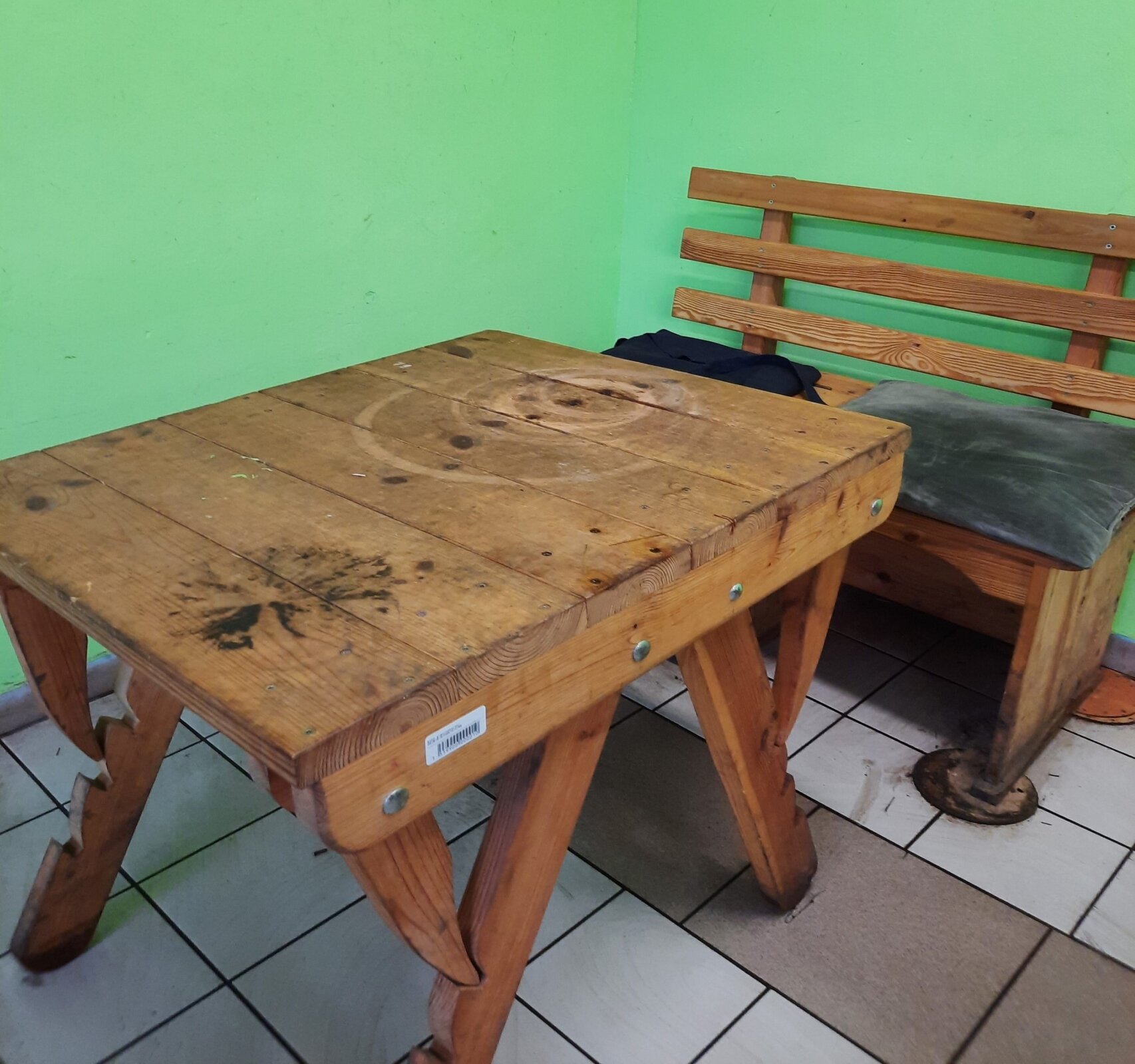 Zdjęcie przedstawia drewniany stół koszykarski oraz ławkę. Stół posiada blat i składane nogi z możliwością regulacji kąta nachylenia blatu. 