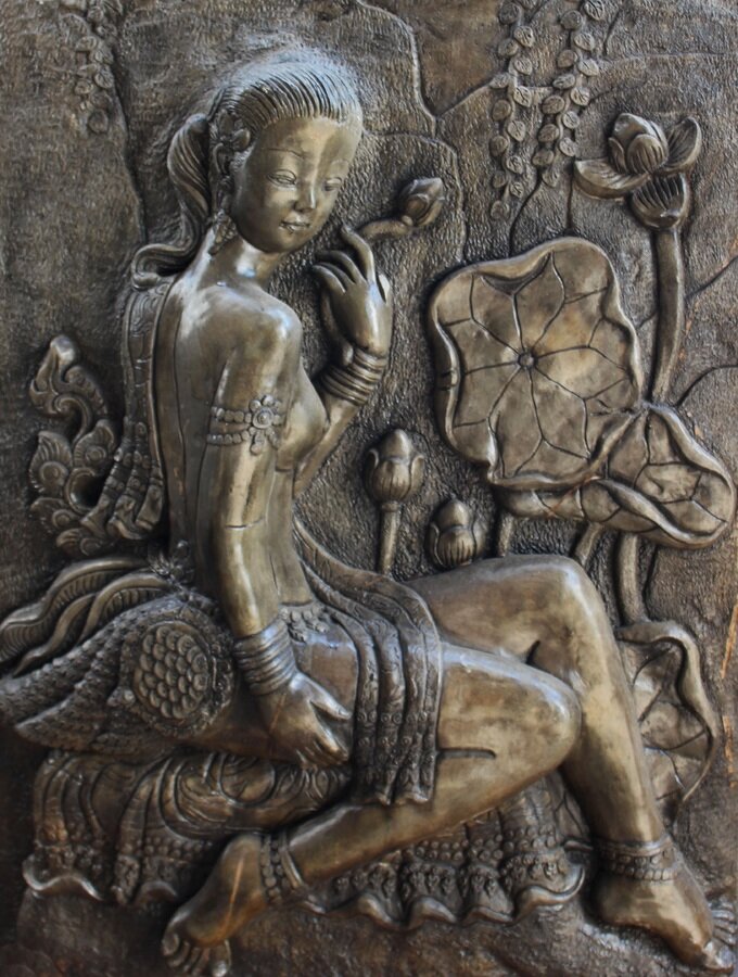 Zdjęcie przedstawia płaskorzeźbę wykonaną w srebrze. Ukazana jest tu postać młodej, wpółnagiej kobiety siedzącej pośród kwiatów.