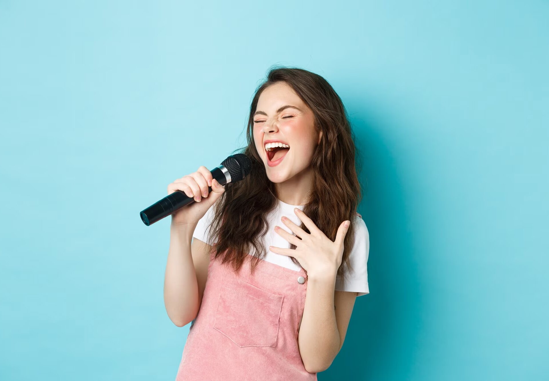 Zdjęcie przedstawia nastoletnią dziewczynę, która śpiewa do mikrofonu trzymanego w dłoni.