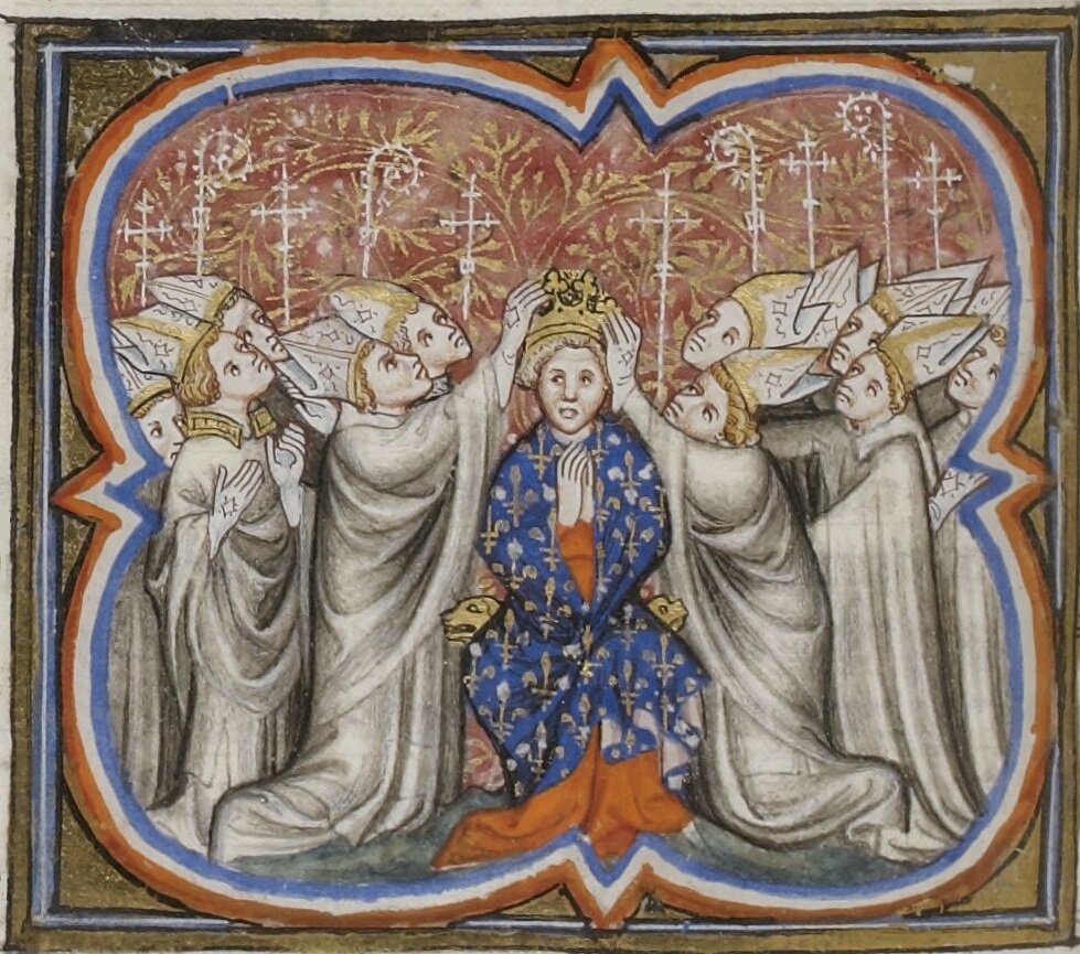 Ilustracja przedstawia koronację na króla. Mężczyzna w niebieskiej szacie ma złożone ręce, biskupi zebrani wokół niego zakładają mu na głowę koronę.