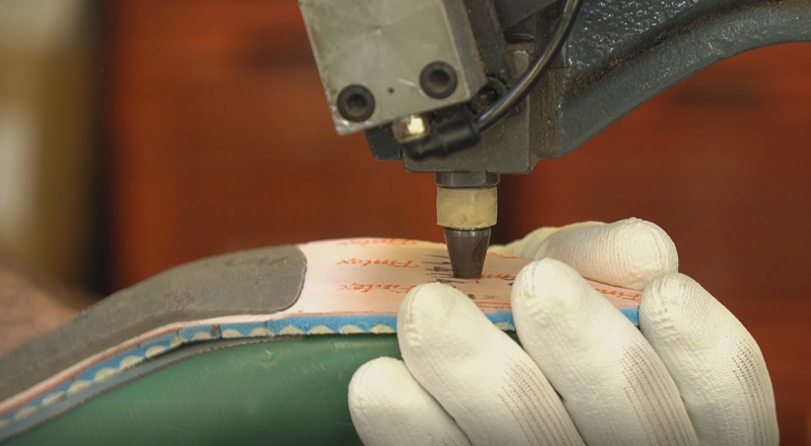 Zdjęcie przedstawia czynność wkręcania elementu za pomocą narzędzia w podeszwę buta. Nagranie tożsame z treścią.