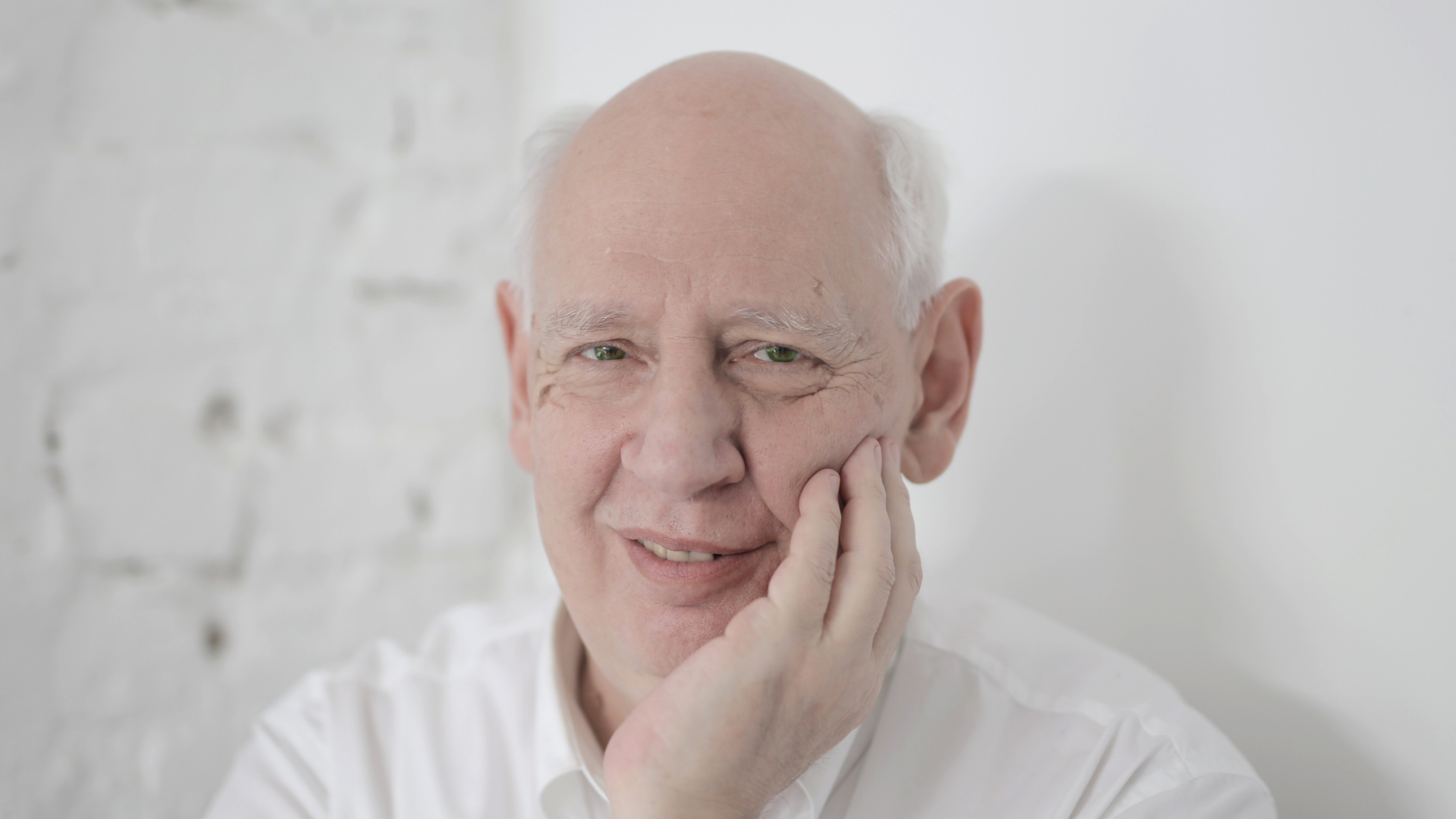 Zdjęcie przedstawia starszego, siwego i częściowo łysego mężczyznę. Mężczyzna uśmiecha się.
