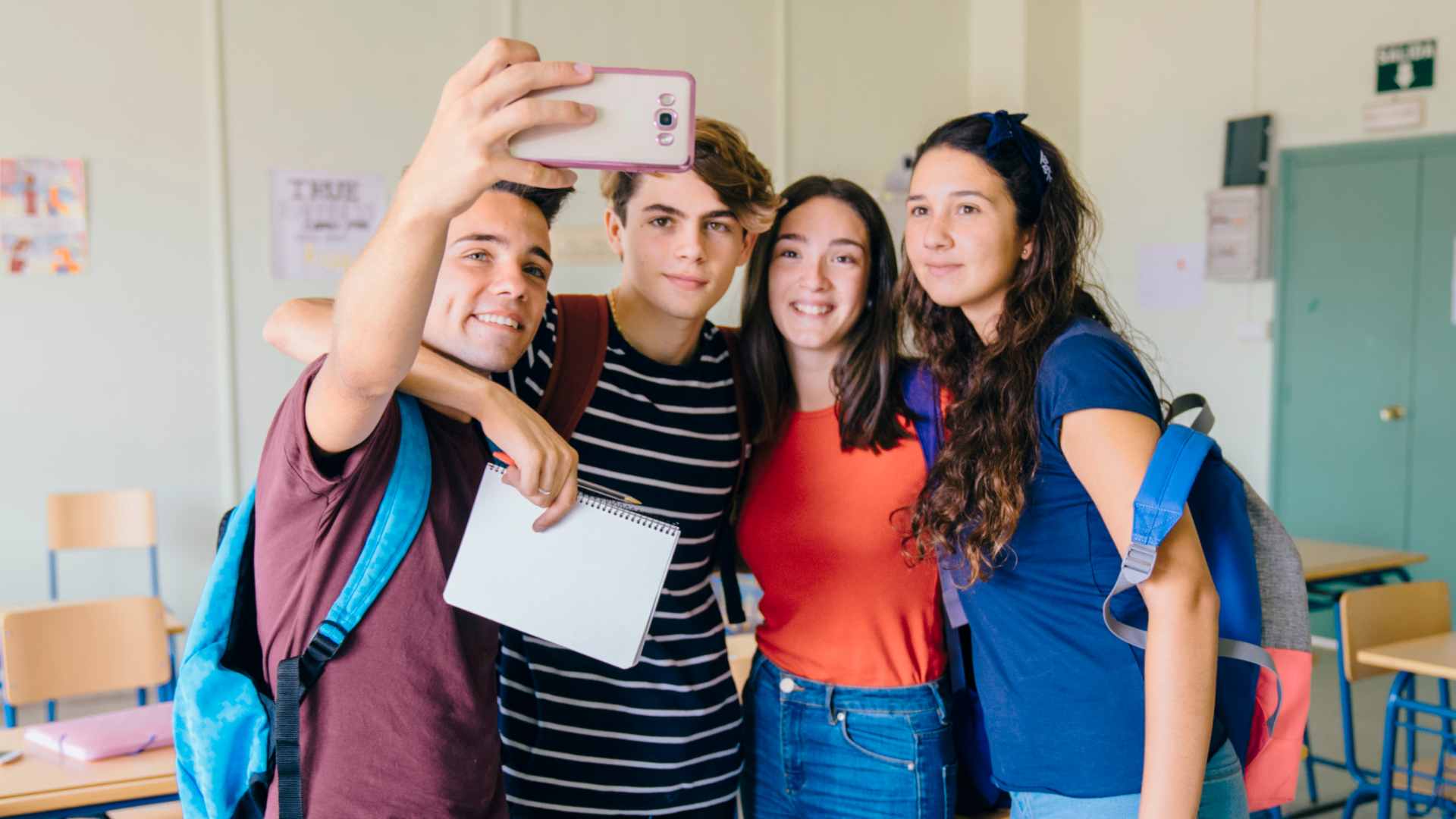 Zdjęcie przedstawia czworo nastolatków, dwie dziewczyny i dwóch chłopaków, który robią sobie zdjęcie typu selfie.
