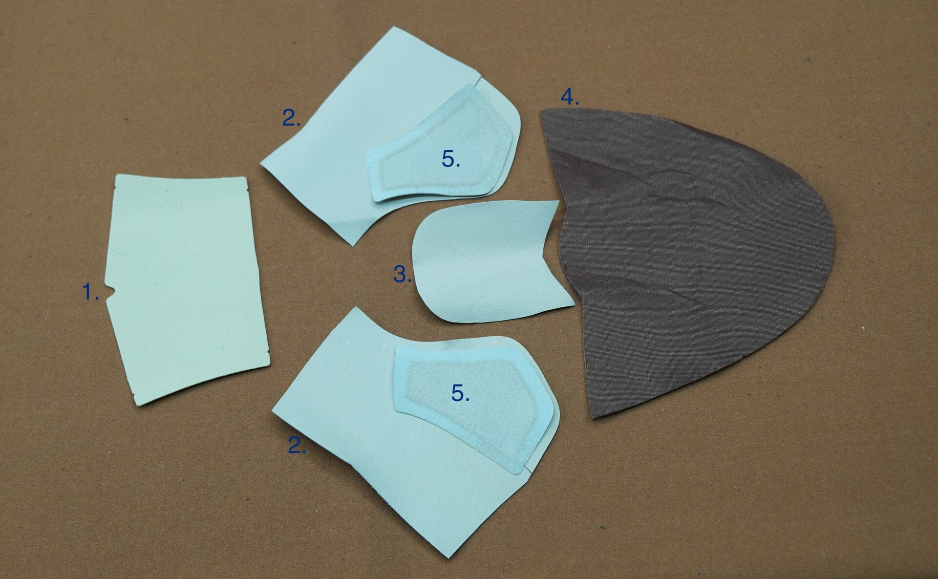 Zdjęcie przedstawia pięć kawałków materiału w różnych kształtach, które stanowią elementy podszewki buta. Nagranie tożsame z treścią.