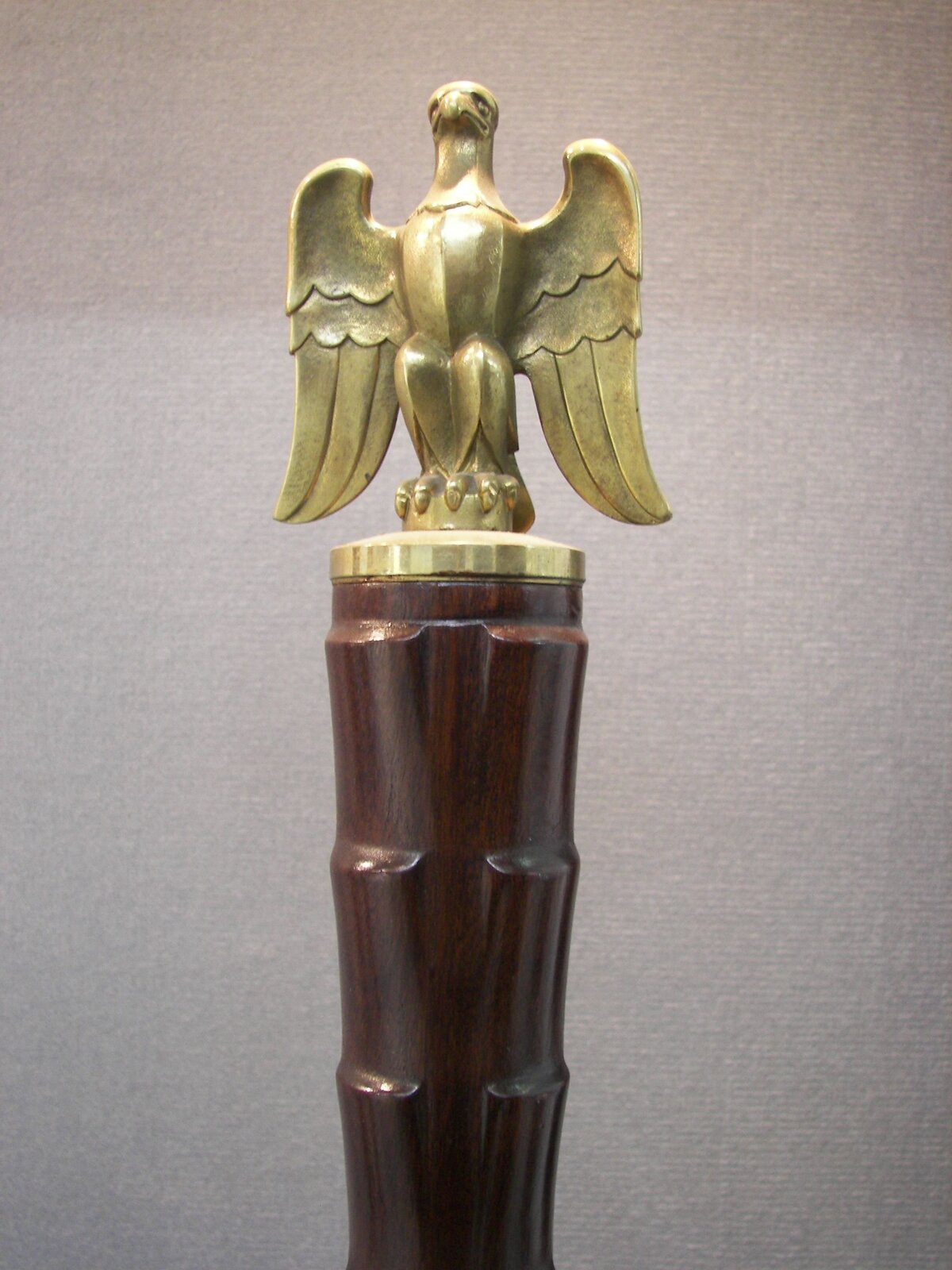 Zdjęcie przedstawia fragment wykonanej z drewna laski marszałkowskiej. Laskę wieńczy figura orła. To tak zwana głownia laski.