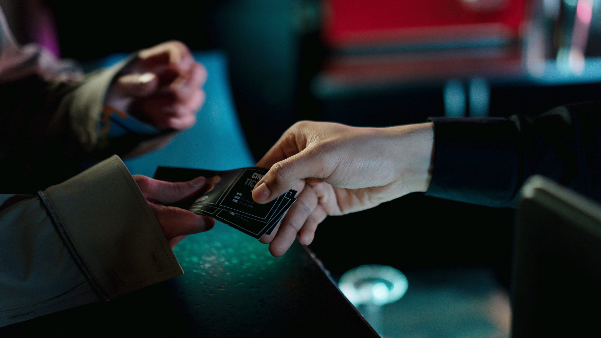 Zdjęcie przedstawia gest zakupu kilku biletów. Na zdjęciu widoczne są dłonie dwóch osób. Jedna osoba/kasjerka podaje bilety drugiej.