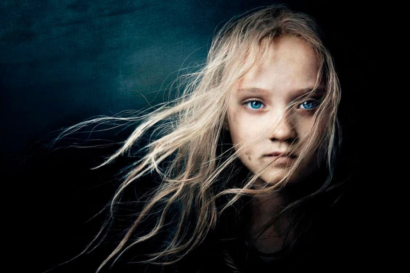 Fotografia portretowa przedstawia dziewczynkę z rozwianymi włosami. Nie jest to portret beztroskiego dziecka, ale silnej młodej osoby przygotowanej na najgorsze.