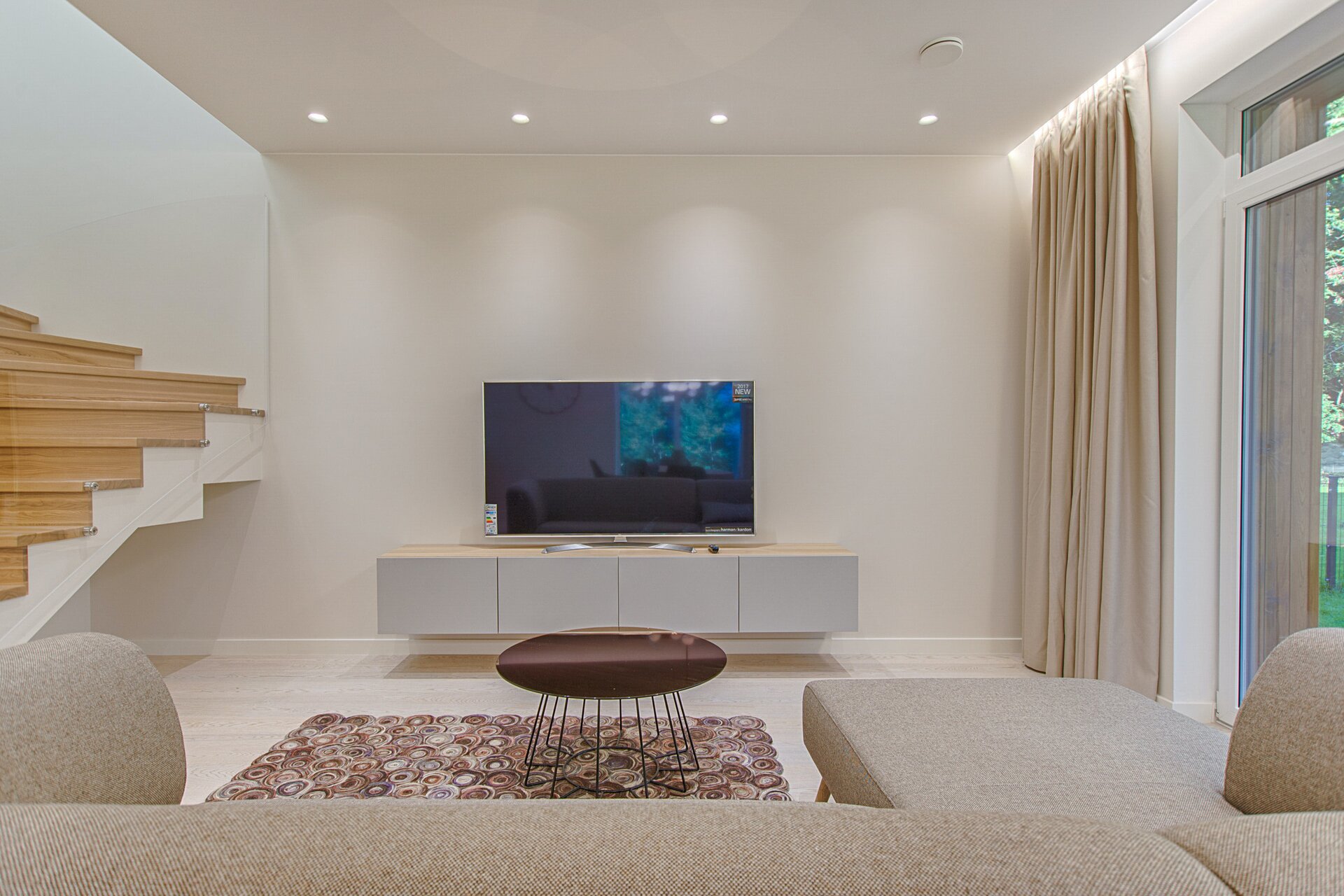 Ilustracja przedstawia salon z dużym telewizorem.