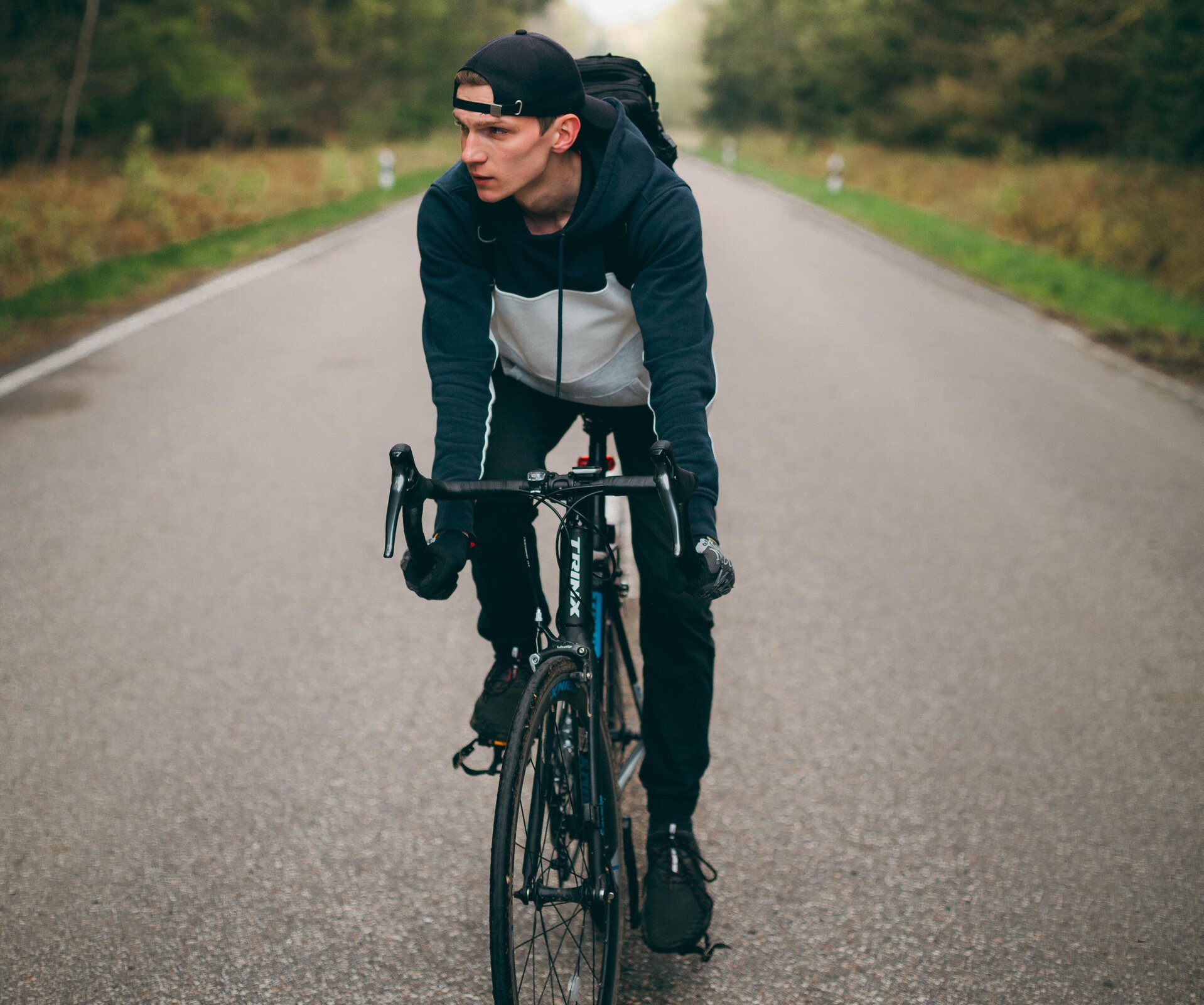 Na ilustracji znajduje się chłopiec jadący po ulicy rowerem.