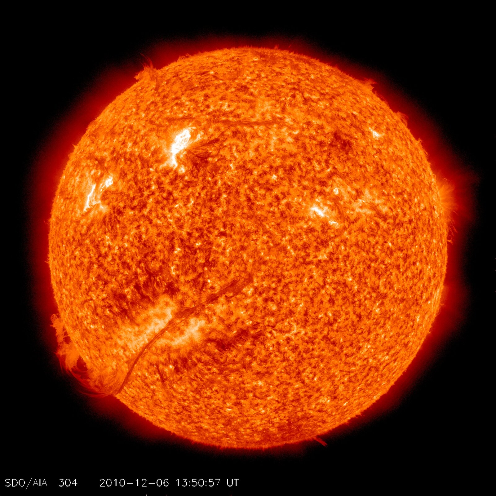 Fotografia prezentuje żółto‑pomarańczową rozżarzoną tarczę Słońca na czarnym tle.