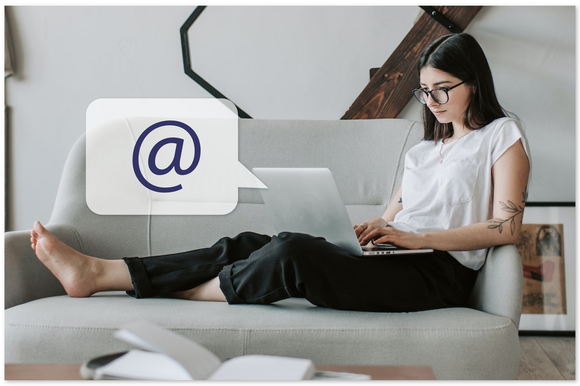 Ilustracja przedstawia młodą kobietę siedzącą na kanapie z laptopem na kolanach. Obok dymek ze znakiem "at".