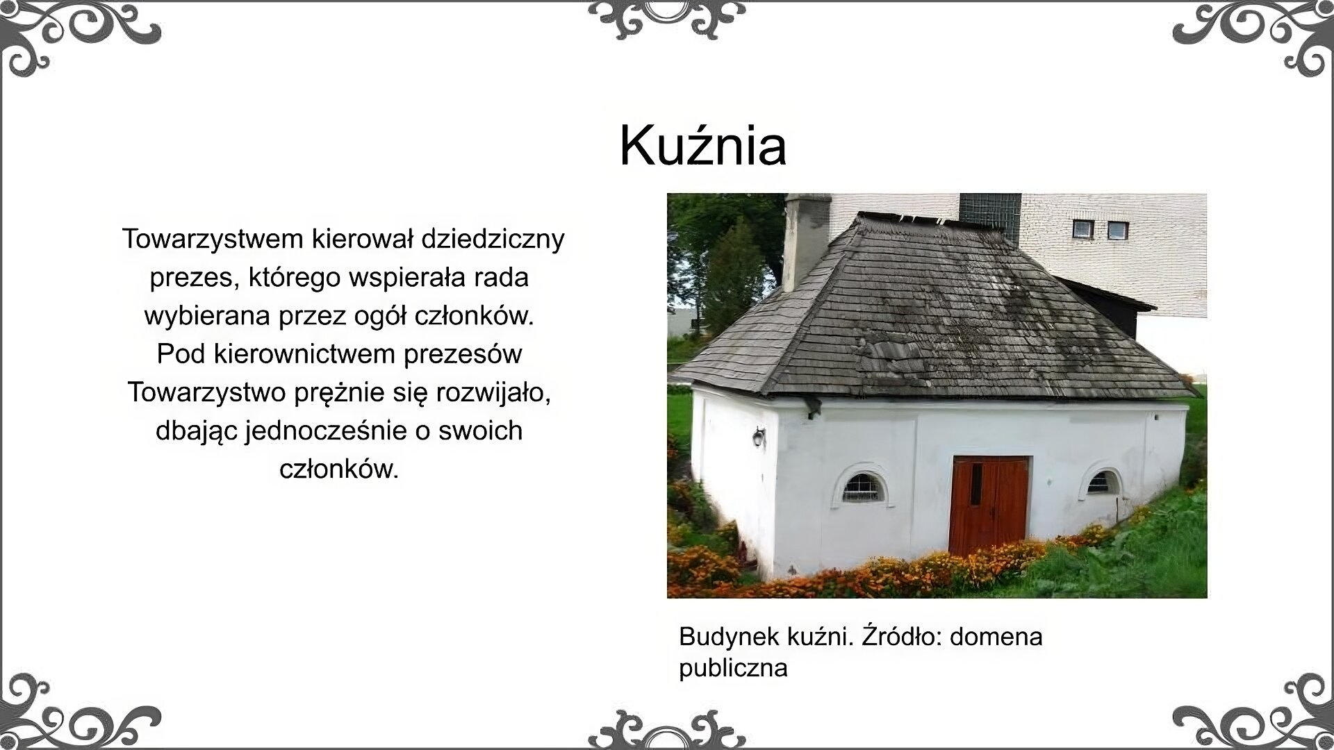 Slajd zatytułowano: Kuźnia. Poniżej znajduje się ilustracja, która przedstawia współczesne zdjęcie budynku kuźni, która została wzniesiona przez władze Hrubieszowskiego Towarzystwa Rolniczego. Jest to niewielki parterowy budynek murowany, przykryty stromym dachem. Obiekt jest otoczony trawą i kwiatami, które wznoszą się wyżej na prawym boku budynku, w tle kolejny budynek. Ilustrację podpisano: Towarzystwem kierował dziedziczny prezes, którego wspierała rada wybierana przez ogół członków. Pod kierownictwem prezesów Towarzystwo prężnie się rozwijało, dbając jednocześnie o swoich członków. 