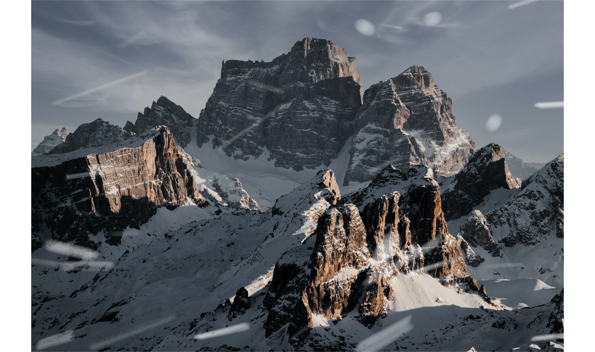 Zdjęcie przedstawia zbliżenie na fragment skalistych szczytów górskich. Szczyty gór pokryte są śniegiem.