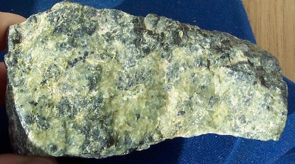 Zdjęcie przedstawia zbity, drobnoziarnisty minerał. Ma żółtą i szarą barwę. 