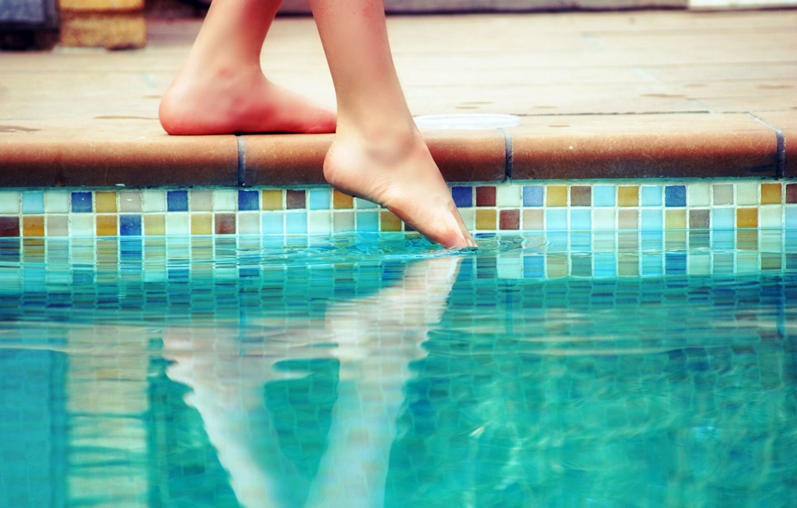 Zdjęcie przedstawia osobę zanurzającą stopę w basenie.