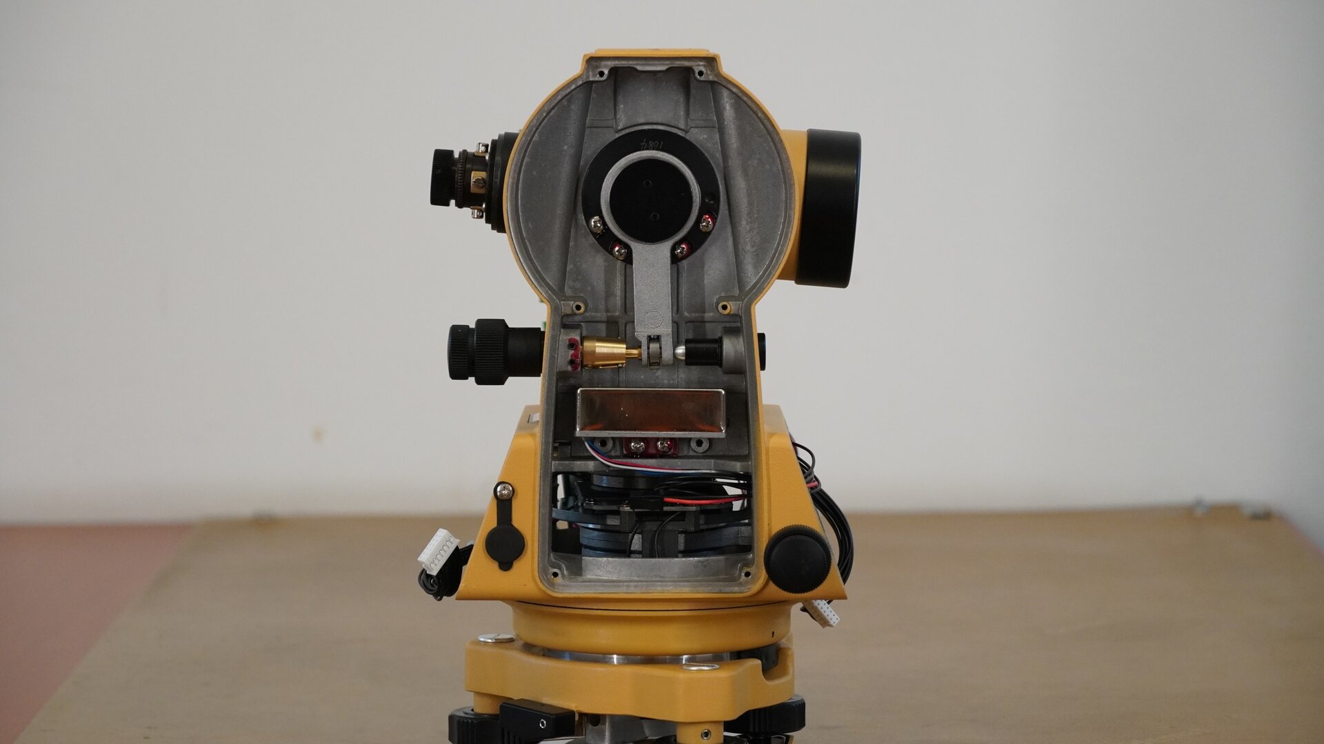 Na zdjęciu ukazano boczne ujęcie tego instrumentu pomiarowego. Po lewej stronie znajduje się okular, a na wprost widoczny jest znajdujący się pod osłoną mechanizm urządzenia. 