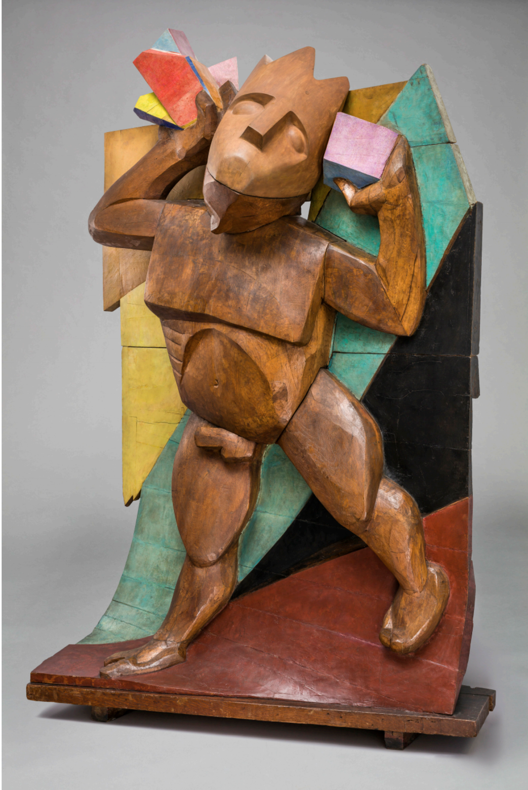 Rzeźba przedstawia karykaturalną postać stworzoną z drewna na podobieństwo Dunikowskiego. Postać ma mocno nakreślone mięśnie nóg oraz brzucha, ma dwie twarze – jedną patrzy pod nogi, drugą uniesioną do góry, spoglądającą w niebo. W dłoniach figurka trzyma różnego rodzaju kostki. Za postacią Dunikowskiego widoczna jest czerwono‑czarno‑zielono‑żółta ściana.