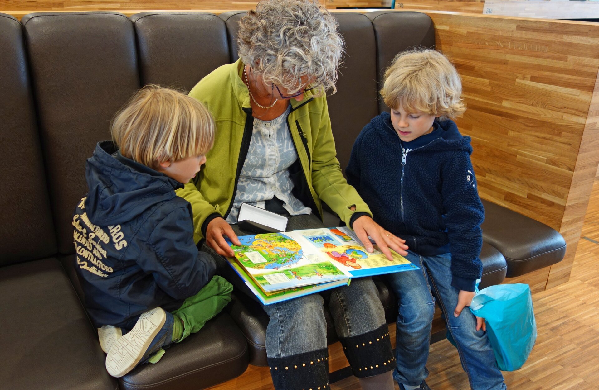 Ilustracja przedstawia babcię czytającą wnukom.