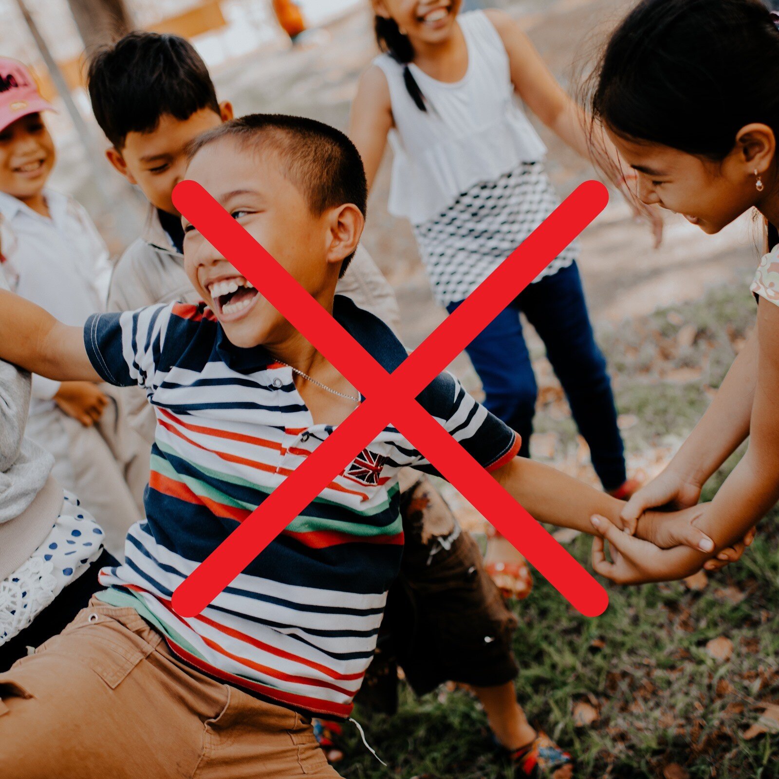 Zdjęcie przedstawia roześmiane, bawiące się dzieci, ubrane w letnie ubrania. Na pierwszym planie widoczny jest roześmiany chłopiec, który ma prawą rękę podniesioną, a za nadgarstek lewej ręki trzyma go dziewczynka. Na ilustrację nałożony jest czerwony znak iks, który przekreśla zdjęcie i symbolizuje zakaz.