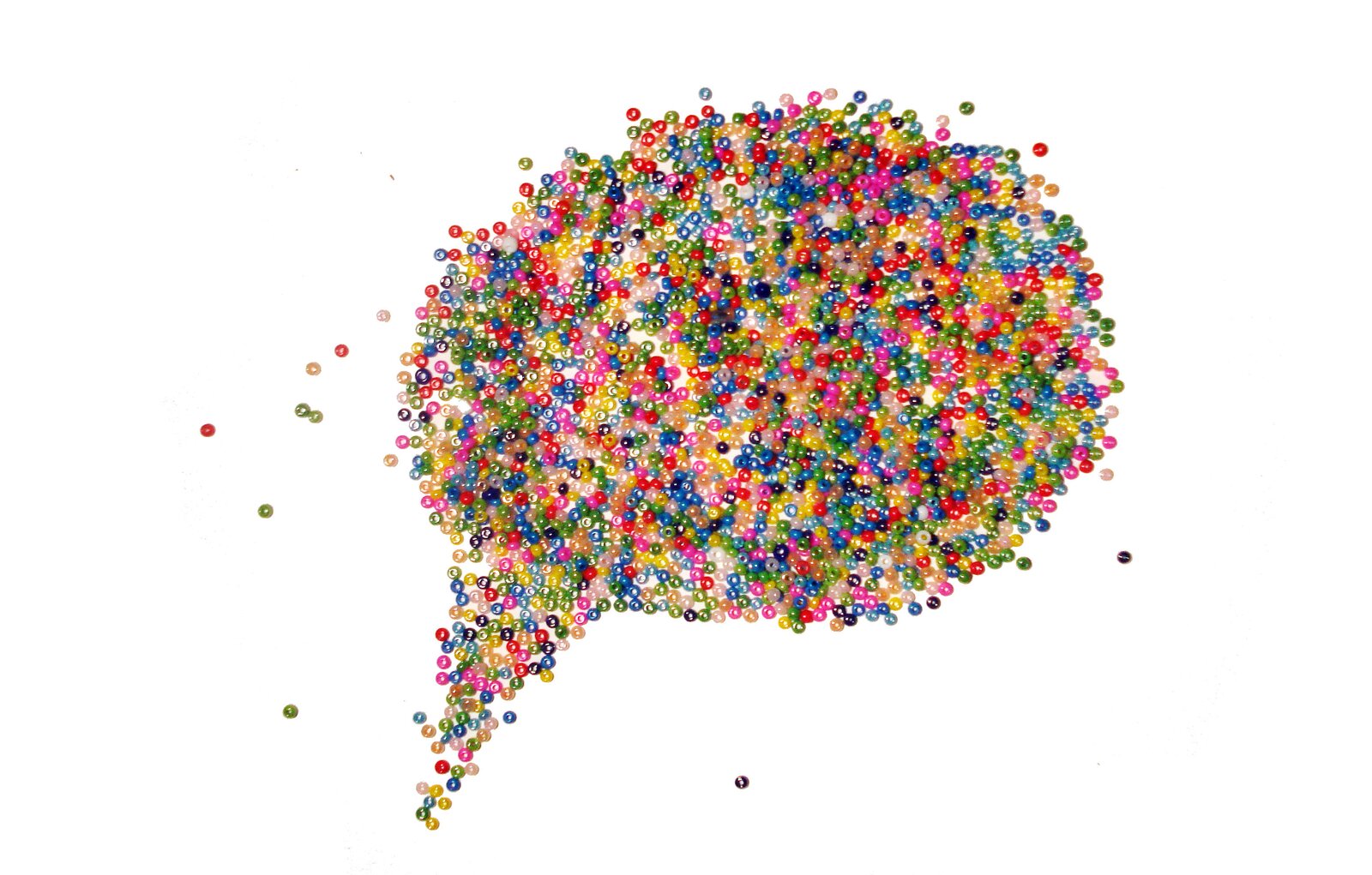 Ilustracja przedstawia rozsypankę kolorowych koralików ułożonych w kształt dymku komiksowego.