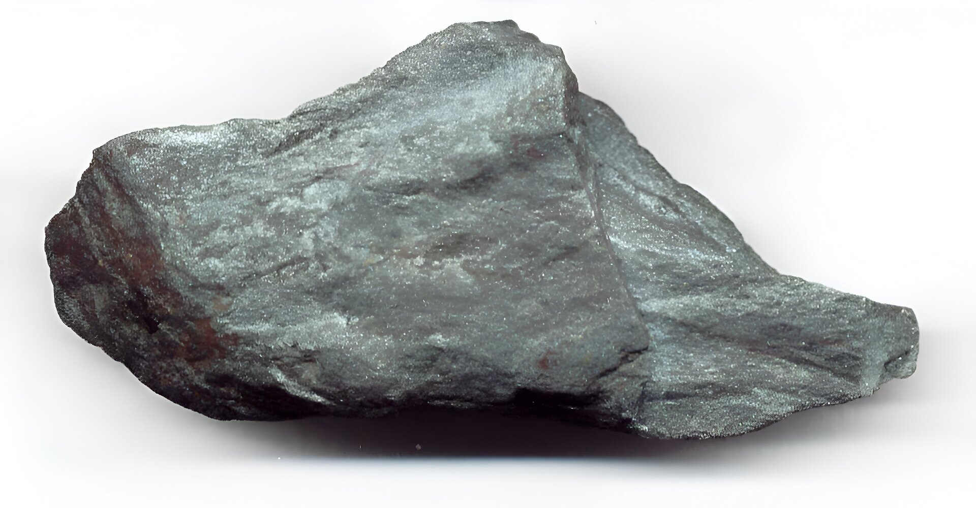 Zdjęcie przedstawia rudę żelaza. Jeden duży szary fragment leży na białym blacie.