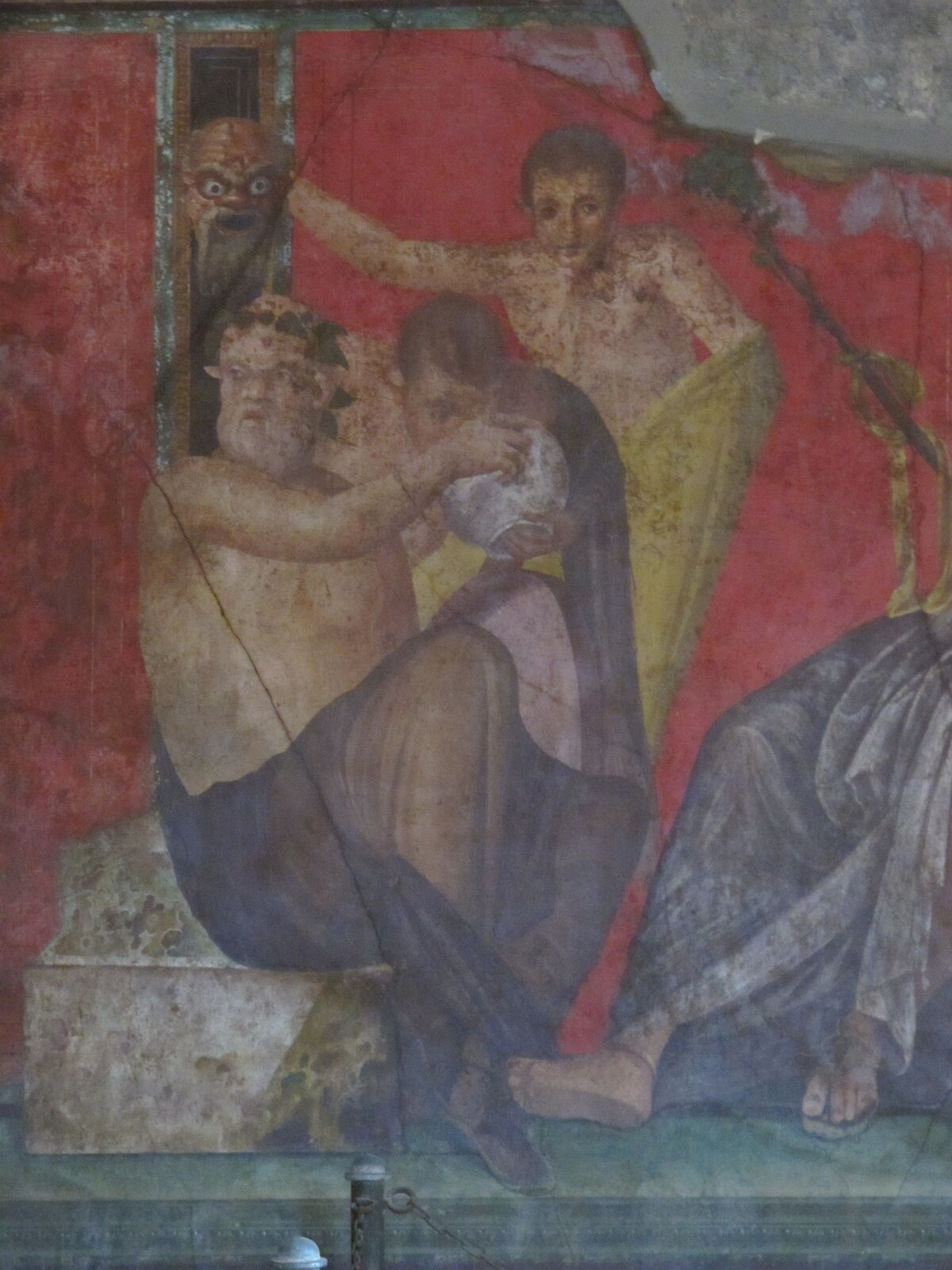 Kolorowa ilustracja przedstawia pompejański fresk zatytułowany „Trymalchion”. Na czerwonym tle, w centrum obrazu, widnieje mężczyzna siedzący na kamiennych schodach. Jest półnagi, jedynie od pasa w dół przepasany niebieską tkaniną. Ma siwą brodę, a na głowie wieniec. W rękach trzyma dzban z winem. Towarzyszą mu dwaj młodzieńcy. Jeden z ciekawością zagląda do dzbana. Z wąskiego okna wychyla się głowa innego mężczyzny z siwą brodą, łysiną, otwartymi ustami i szeroko otwartymi oczyma. W prawej dolnej części fresku widnieją nogi innego uczestnika uczty