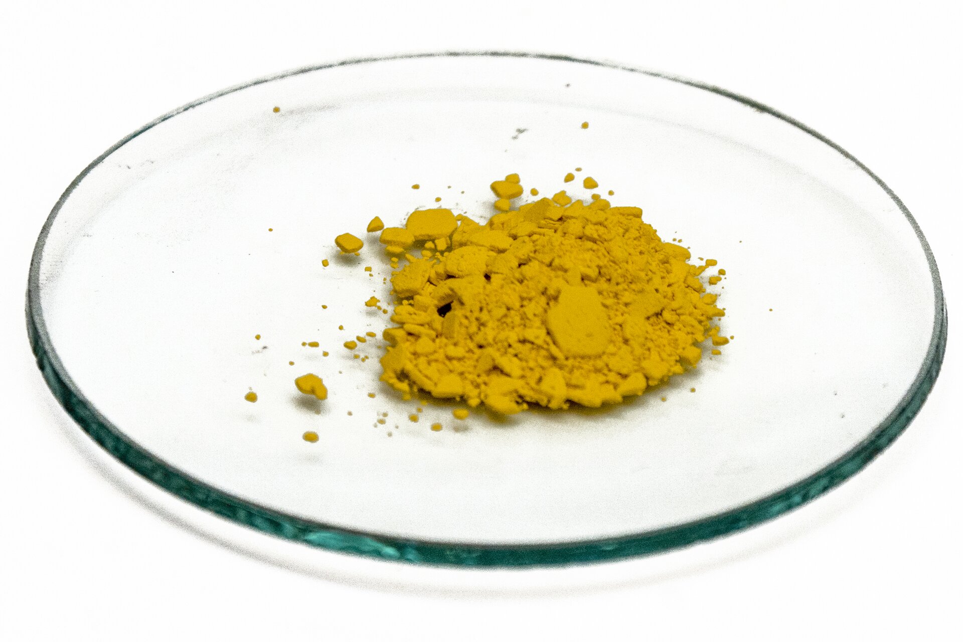 Na zdjęciu na szkiełku zegarkowym jest pewna ilość ciemnożółtego proszku.