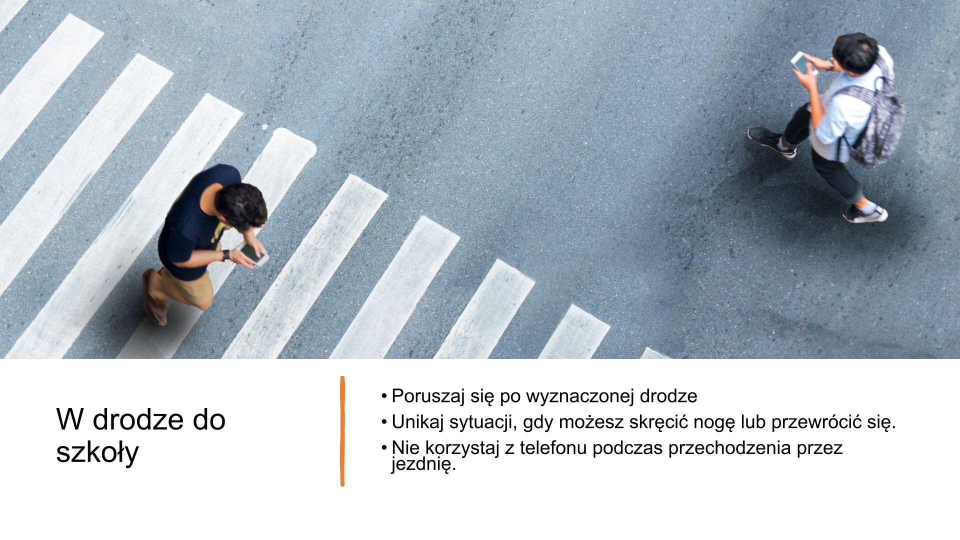 Niebieski slajd, na którym znajduje się tekst i zdjęcie. Znajduje się z prawej strony slajdu i przedstawia przejście dla pieszych z lotu ptaka. Po przejściu przechodzi dwóch mężczyzn, idących w przeciwnym kierunku. Wpatrują się w ekrany swoich telefonów komórkowych. W górnej części slajdu tekst: „W drodze do szkoły”, a po lewej stronie slajdu informacja: „Poruszaj się po wyznaczonej drodze. Unikaj sytuacji, gdy możesz skręcić nogę lub przewrócić się. Nie korzystaj z telefonu podczas przechodzenia przez jezdnię”.