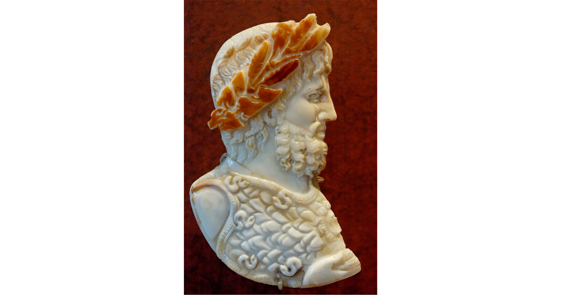 Zdjęcie przedstawia popiersie, rzeźbę boga nieba, burzy i deszczu Jowisza. Zdjęcie przedstawia popiersie Jowisza z profilu. Mężczyzna ma brodę, a na głowie wieniec laurowy.