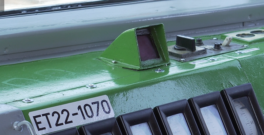 Zdjęcie przedstawia wskaźnik czuwaka aktywnego. Jest on przymocowany do pulpitu. Ma on kształt graniastosłupa trójkątnego, którego jedna z podstaw jest otwarta, w podstawie tej znajduje się ekran. 